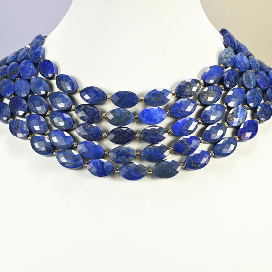 Lapis lazuli faceted flat oval strands arranged as a layered collar on a white display bust, deep blue beads across the neck