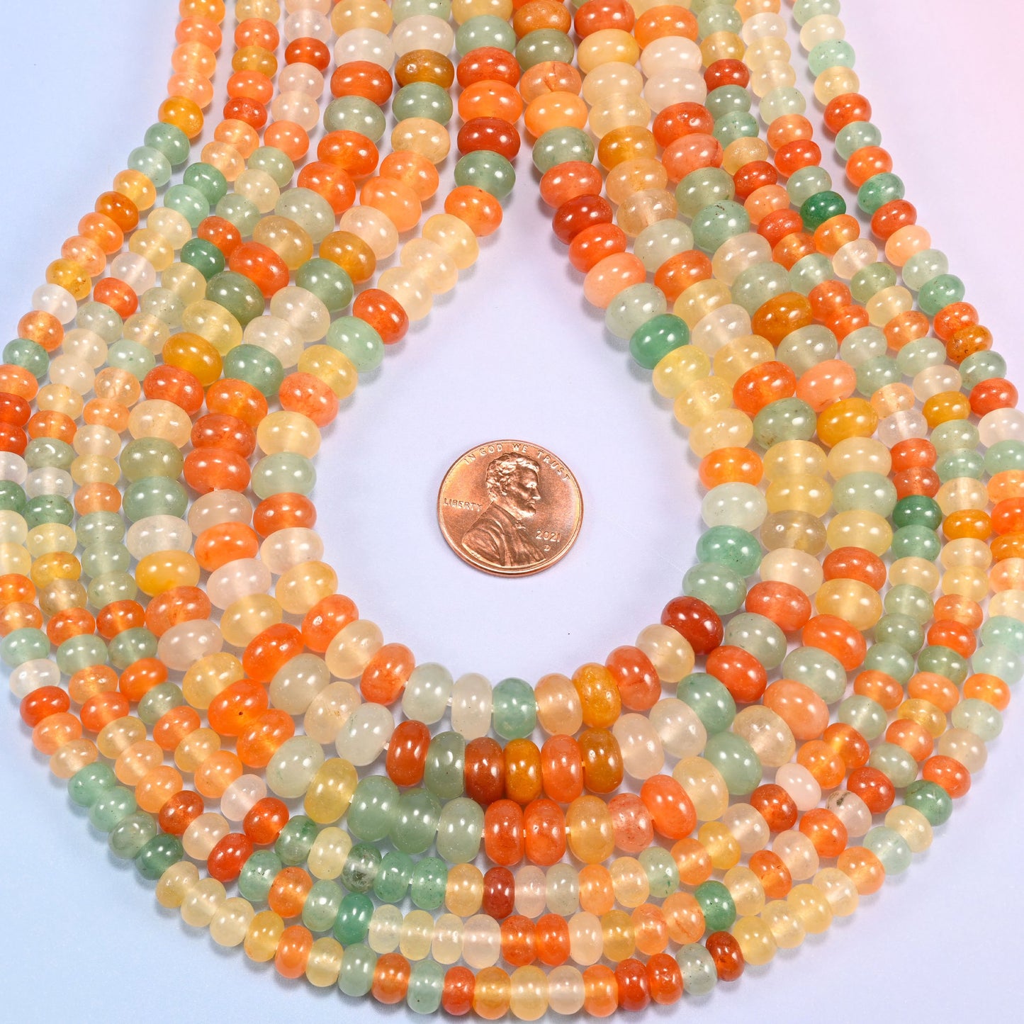 Gold Silk Jade gemstone rondelle beads in a teardrop coil, warm orange and cream discs stacked close together
