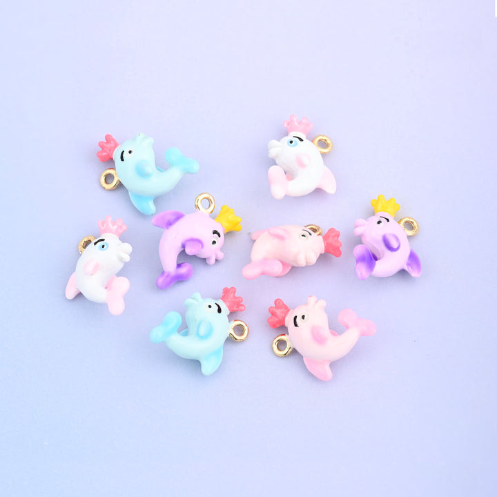Eight dolphin charms with crowns scattered together, enamel in light blue, white, pink and light purple.