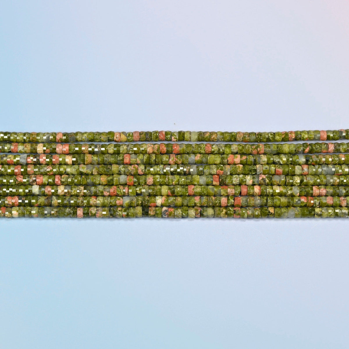 Several strands of unakite faceted heishi disc beads laid in straight rows