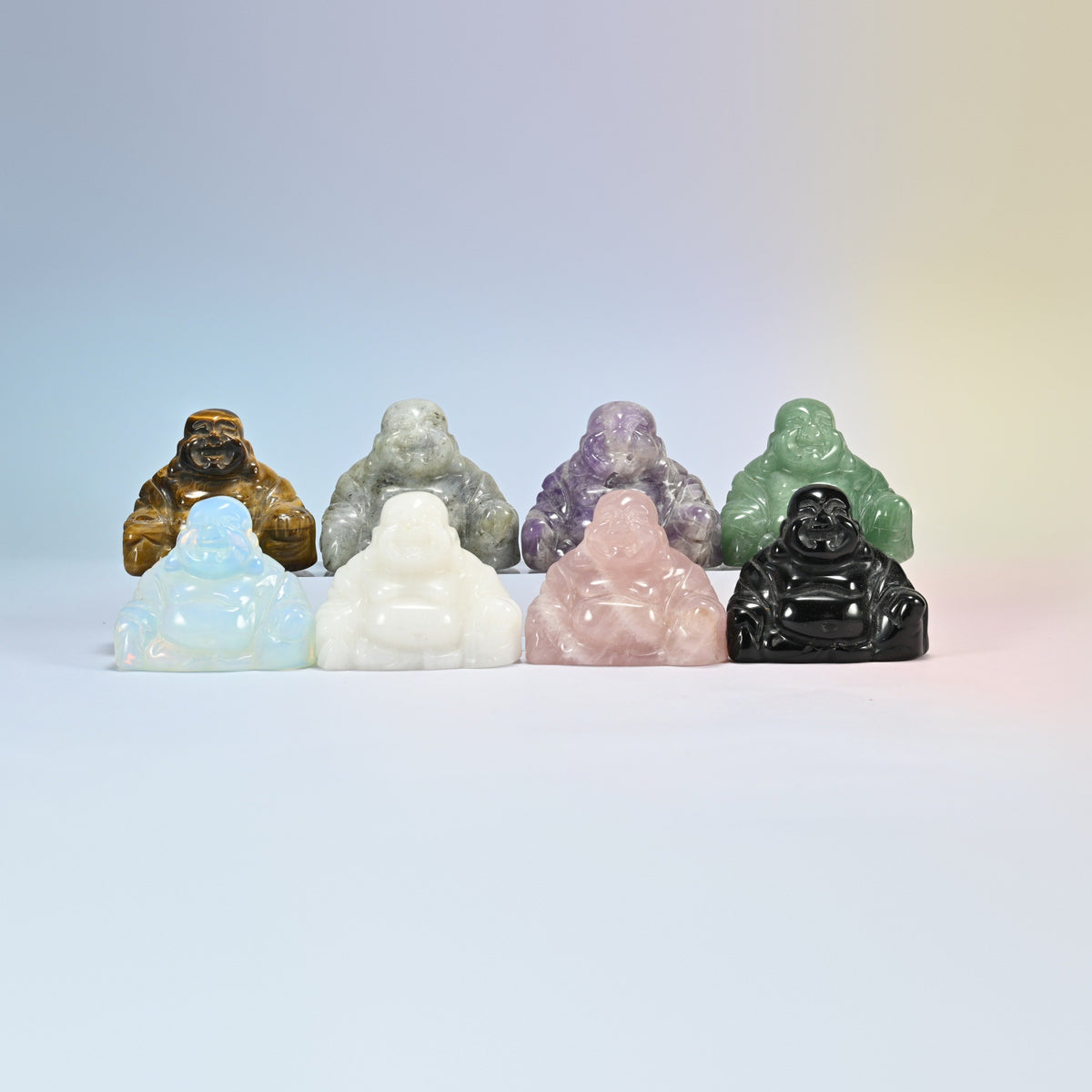 Group of laughing Buddha crystal carvings in tiger eye, white labradorite, amethyst, green aventurine, opalite, white jade, rose quartz and black obsidian
