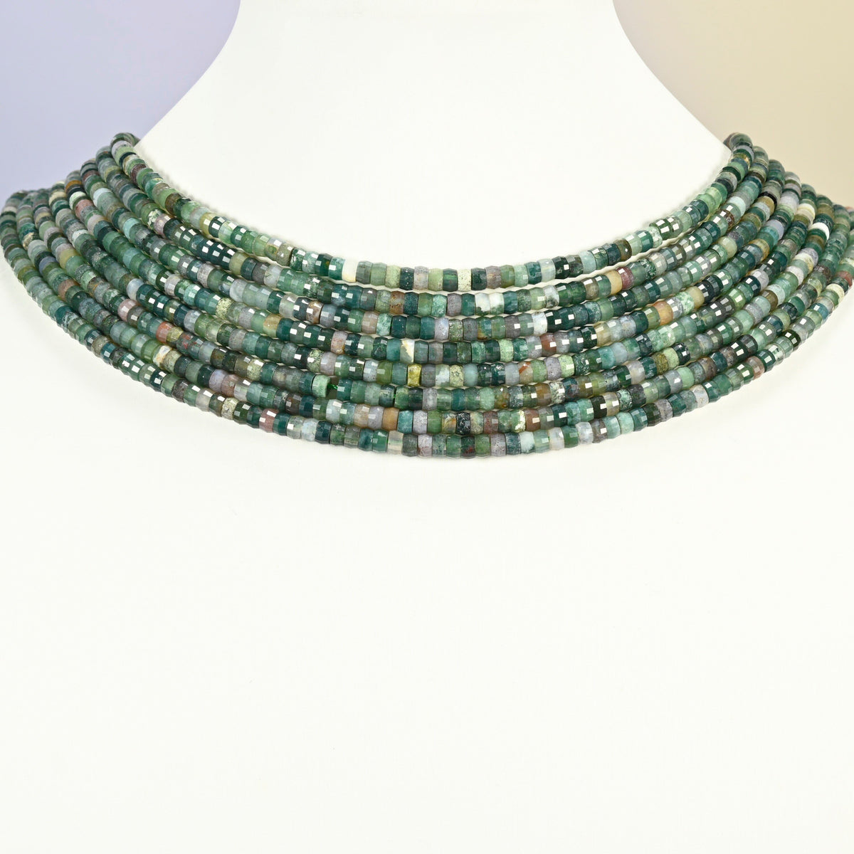 Indian agate faceted heishi disc strands arranged as a layered collar on a white display bust, green beads across the neck