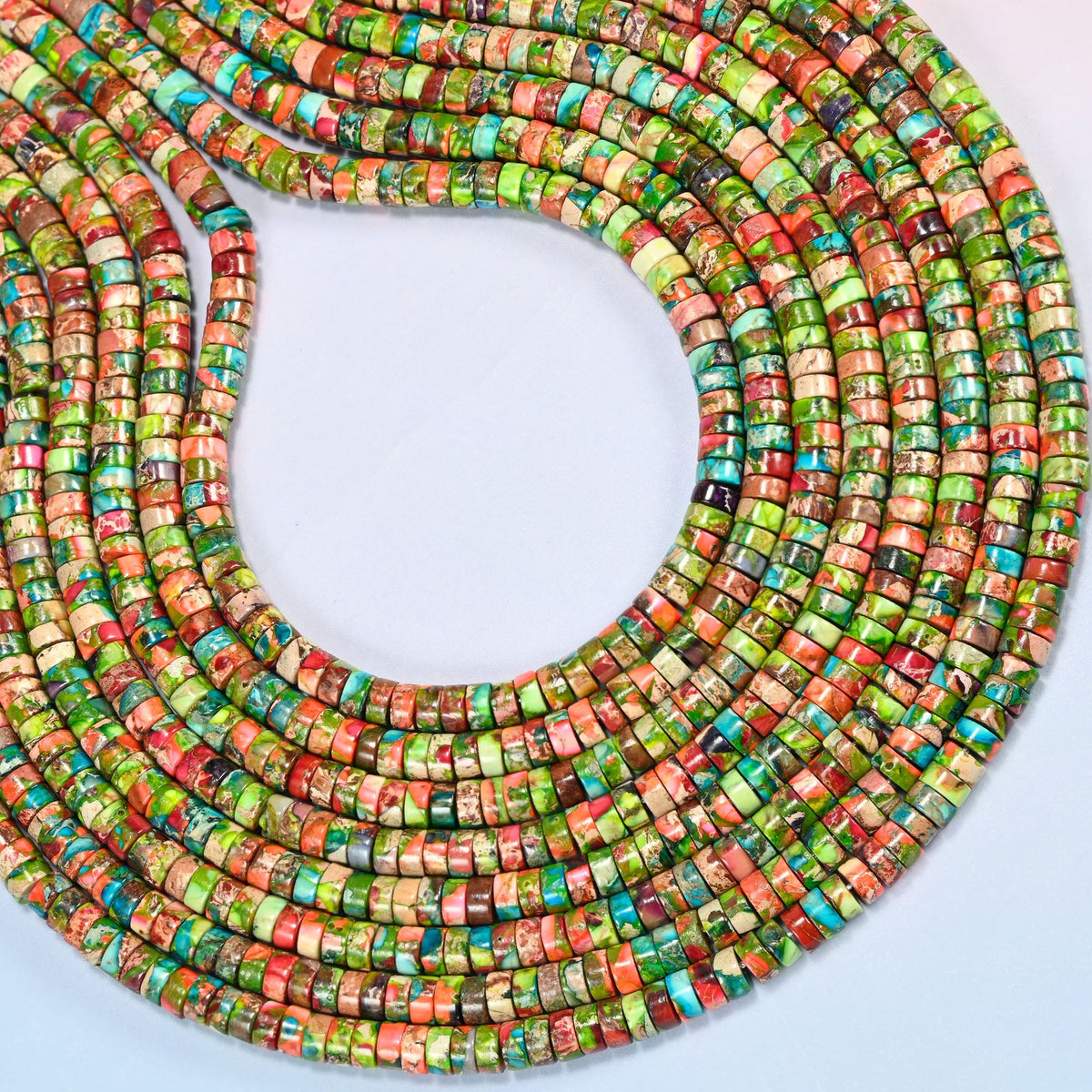 Dyed blue green sea sediment jasper heishi disc beads 2x4mm curved into an open loop, showing the green and coral mix across whole strands