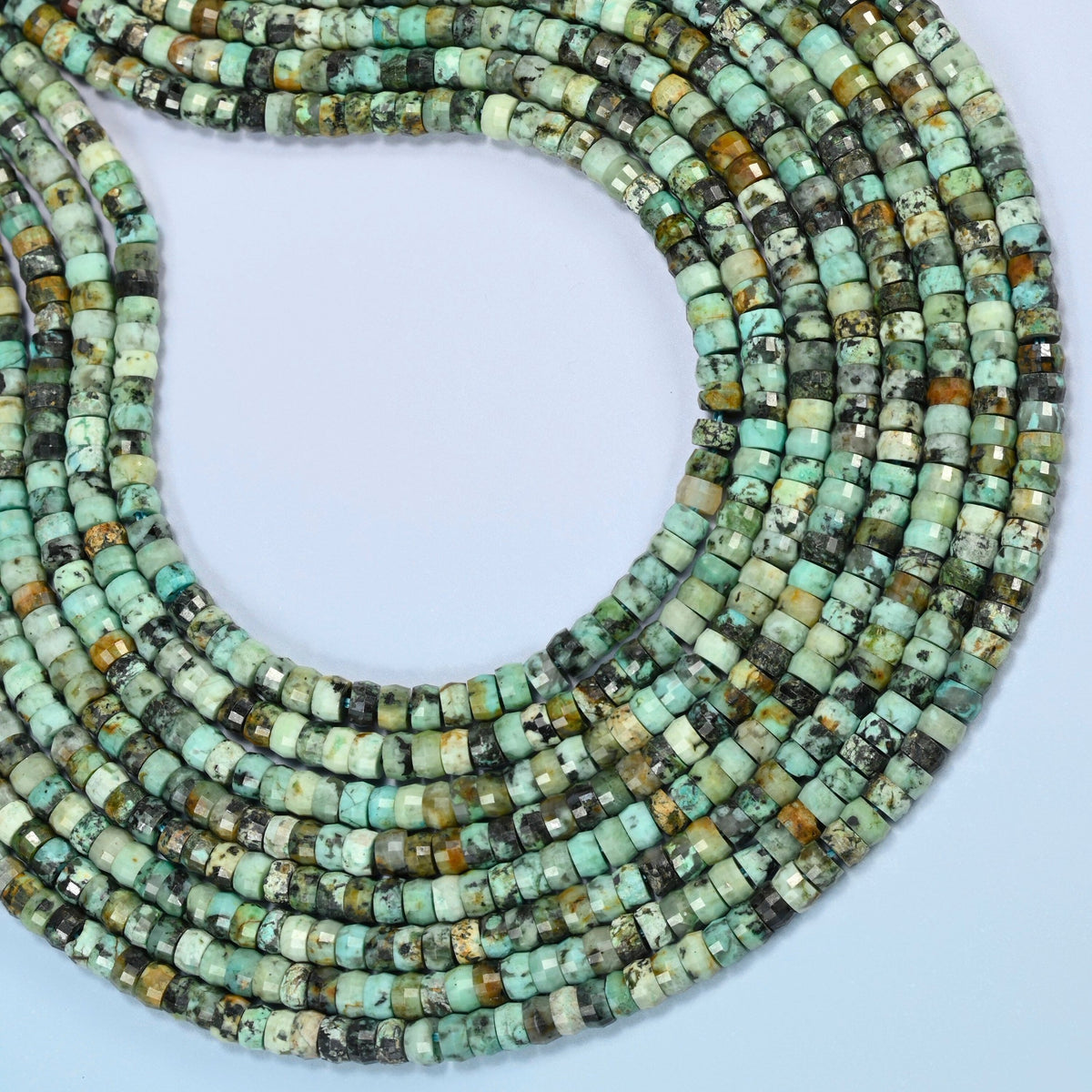 African howlite faceted heishi disc beads curved into an open loop, turquoise green beads with black and brown matrix