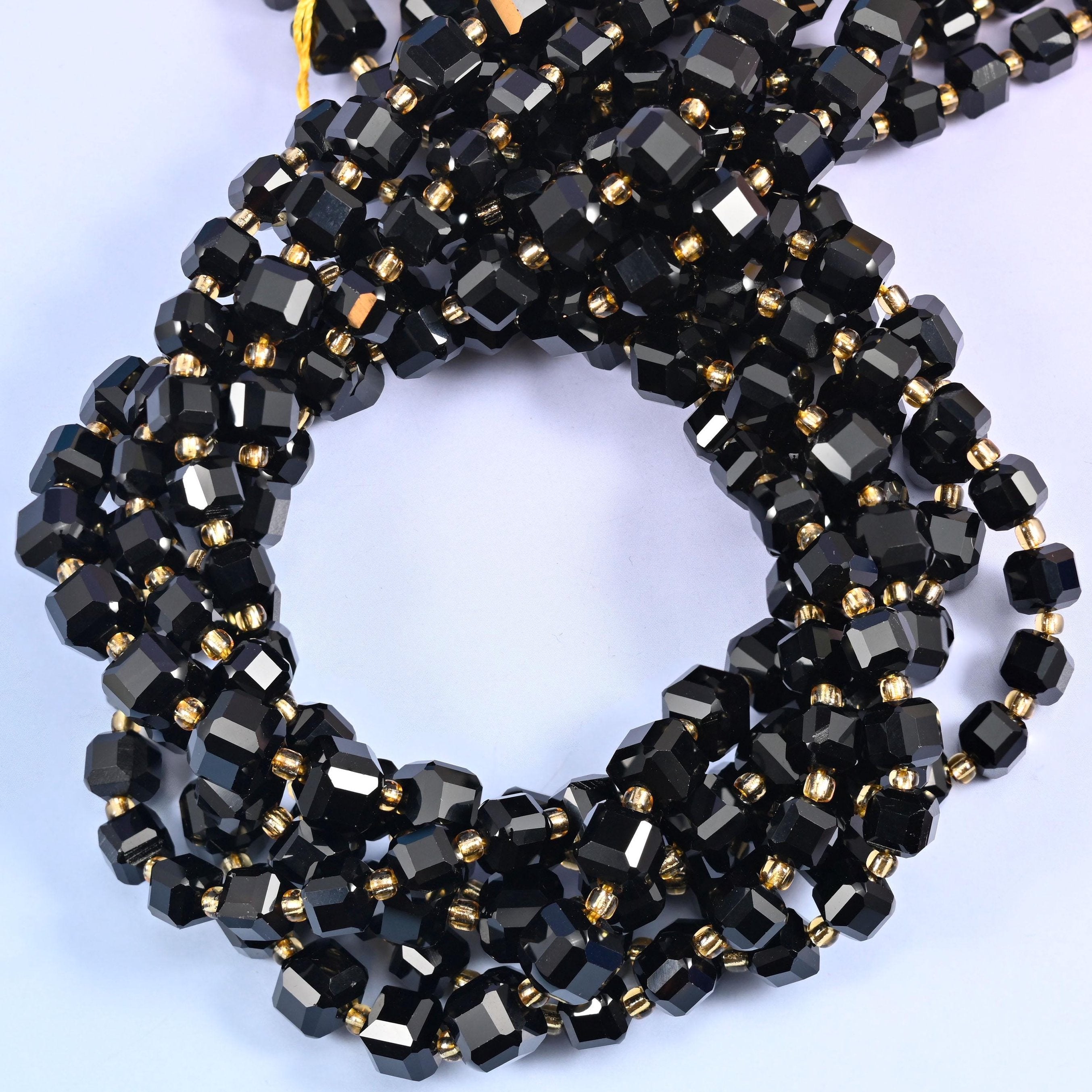 Solid jet black cubes with the corners cut away into facets, polished to a hard mirror gloss that picks up a white highlight on every face. Dense