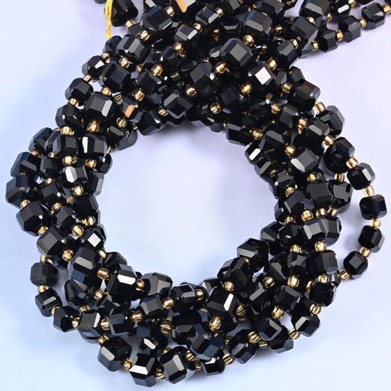 Solid jet black cubes with the corners cut away into facets, polished to a hard mirror gloss that picks up a white highlight on every face. Dense