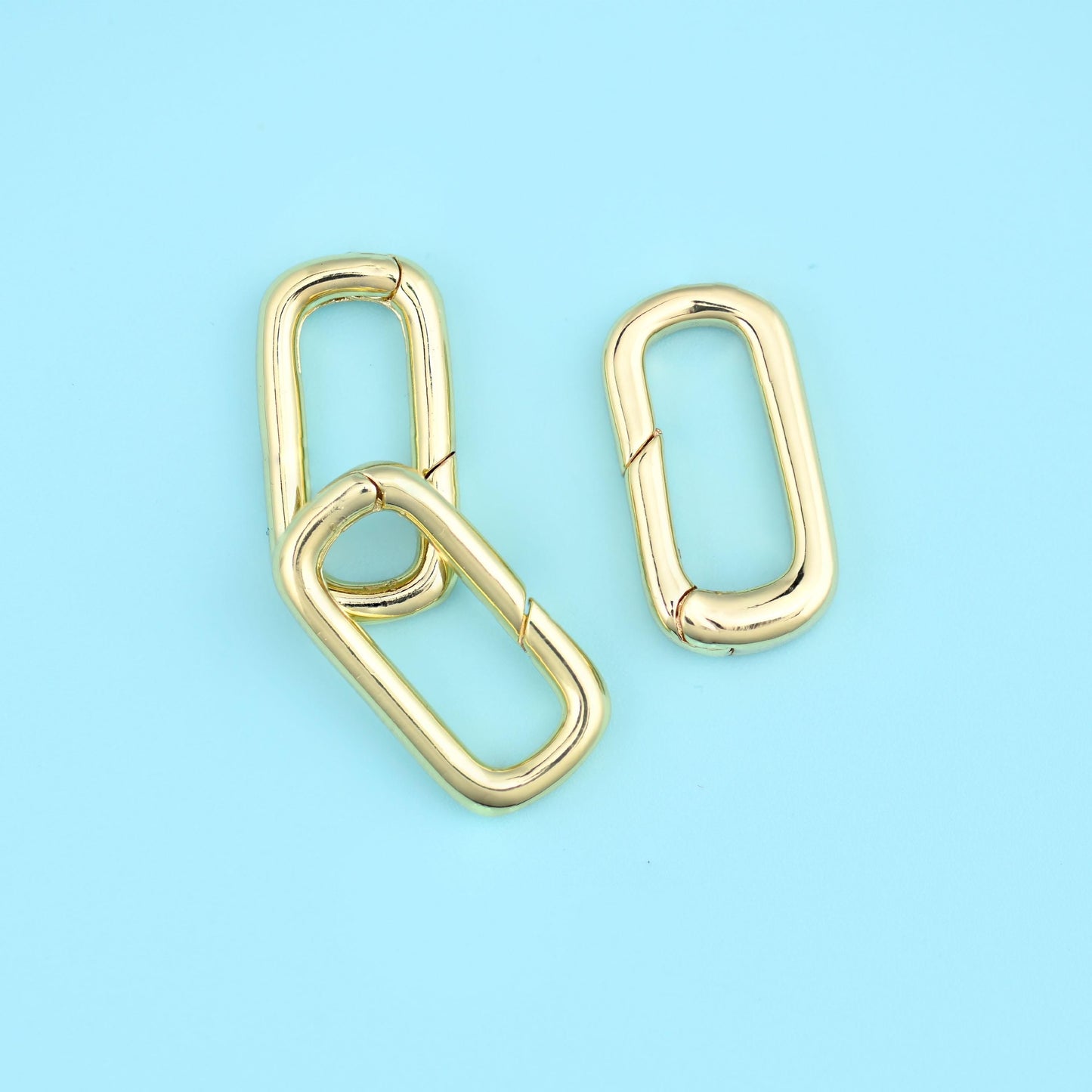 A slim rounded-rectangle carabiner with a spring gate along one long side — press it open, hook it on, and it snaps shut.…