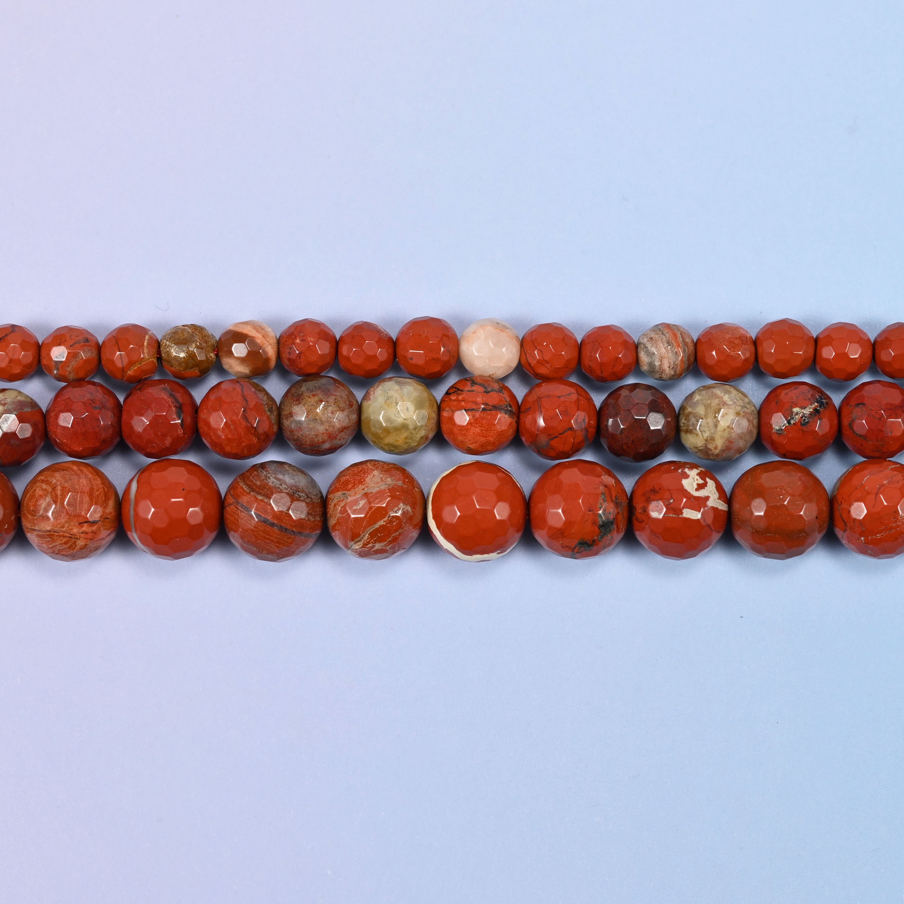Full 15-inch strand of flower red jasper round beads laid out for jewelry making.