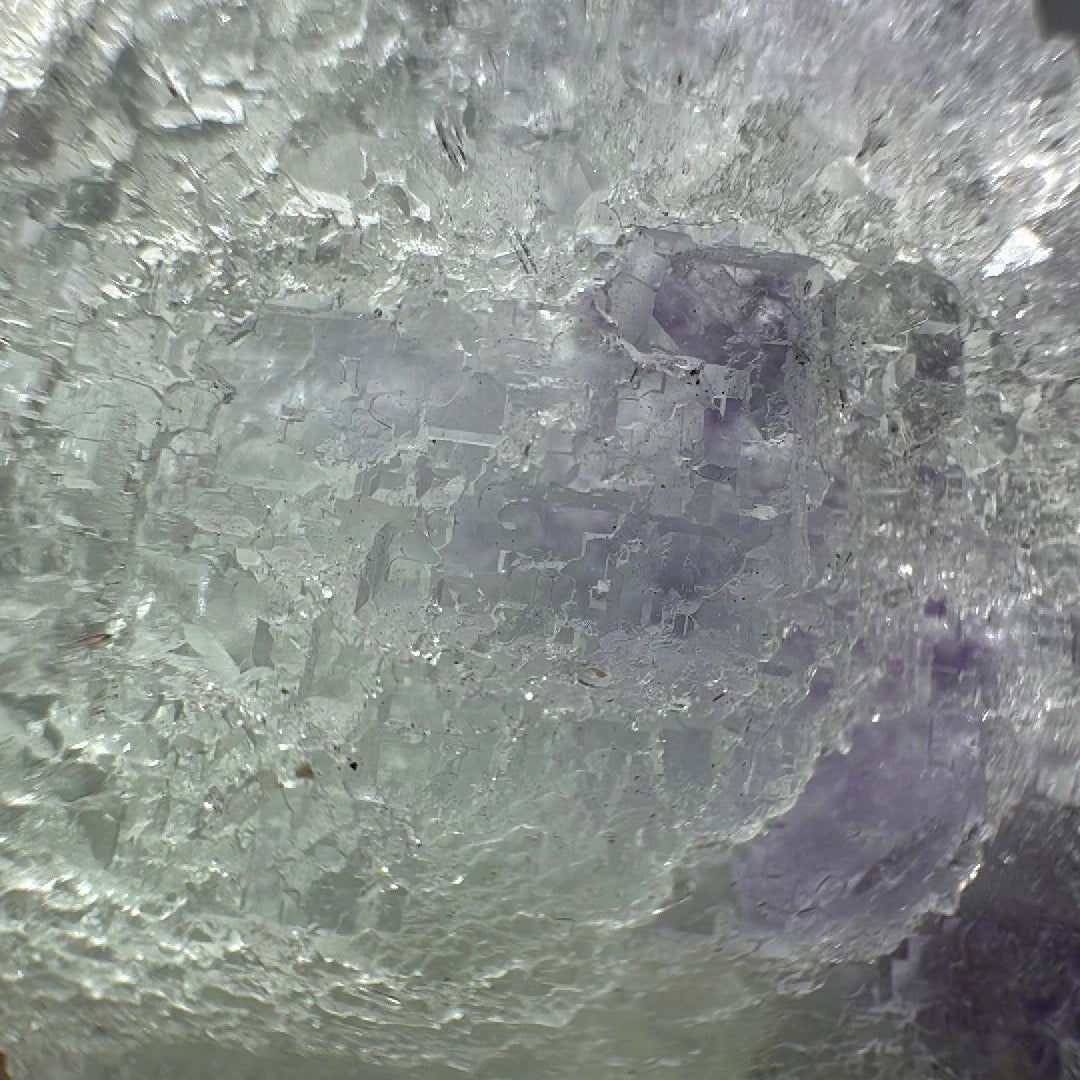 Macro crop of the purple fluorite zone beneath a dusting of tiny white quartz crystals