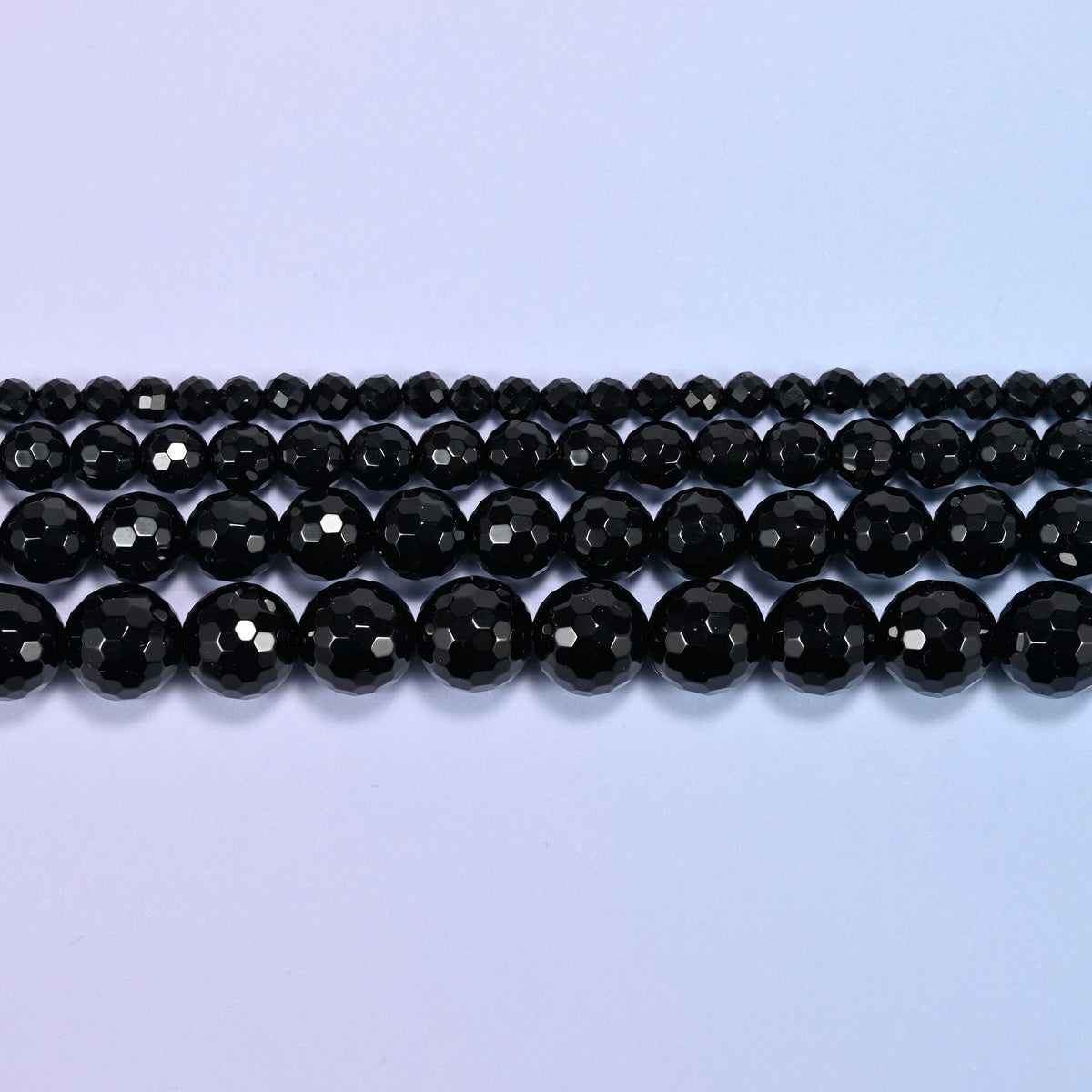 Black onyx faceted round beads in three straight rows, bead size growing from the back row forward.