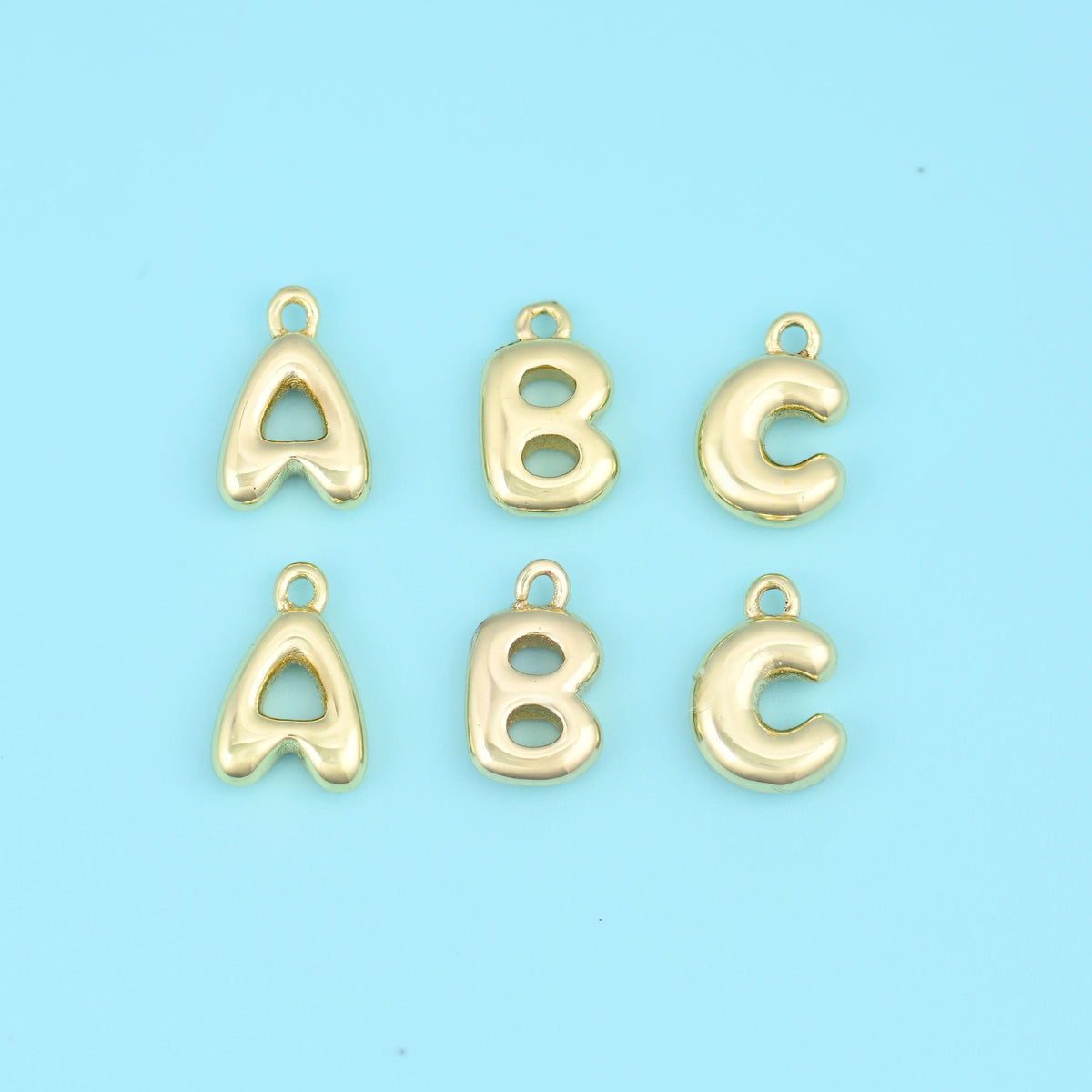 18K gold plated letter pendants, the initials A, B and C in puffed balloon-style gold, shown in two rows.