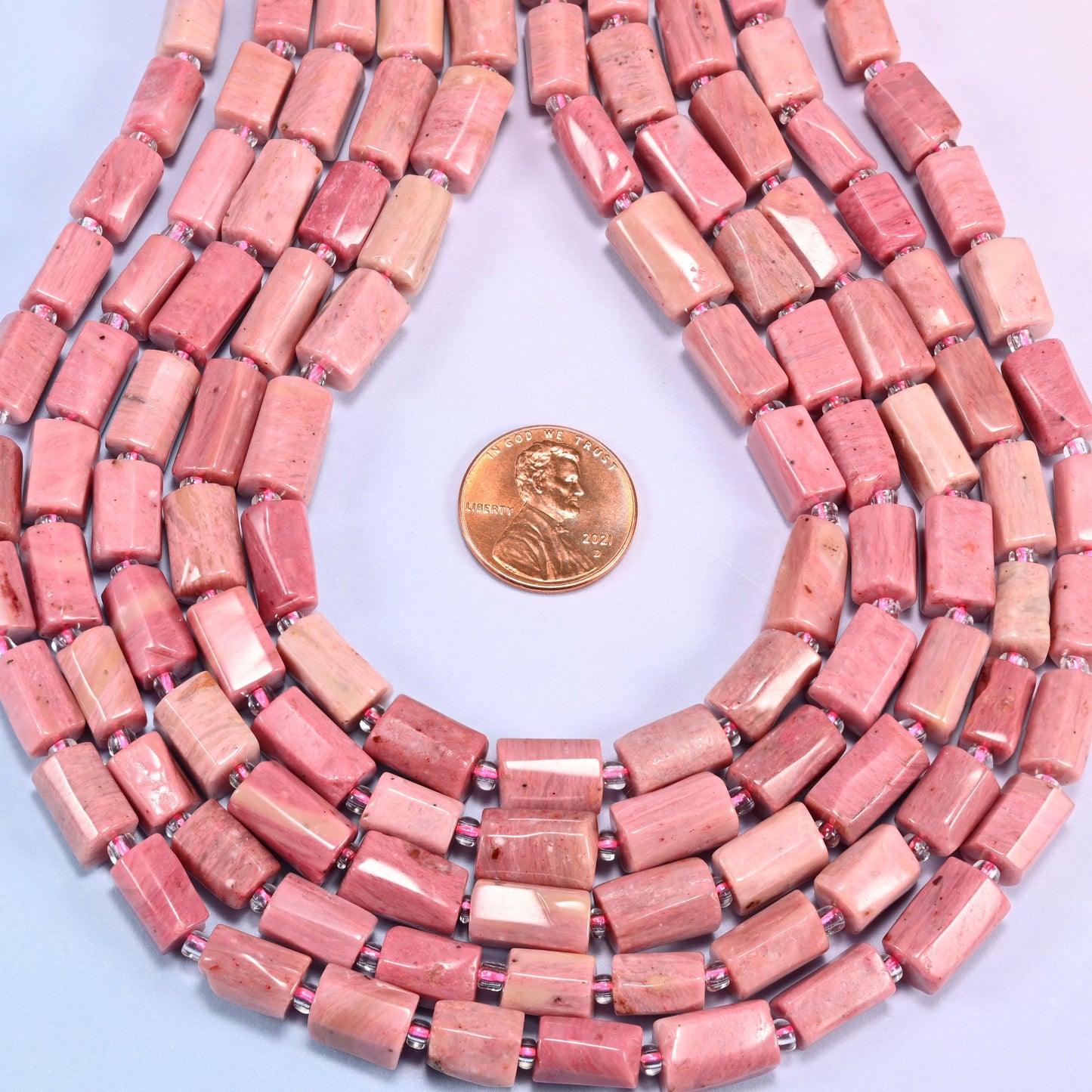 Pink Rhodonite faceted tube beads in a teardrop coil, bead length running 9mm to 11mm along the strand at a steady 7mm width