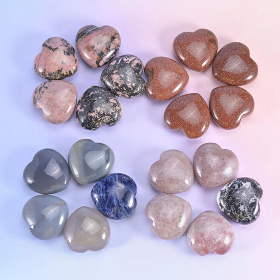 Pink speckled rhodonite hearts next to brown, grey and blue-flecked sodalite carvings