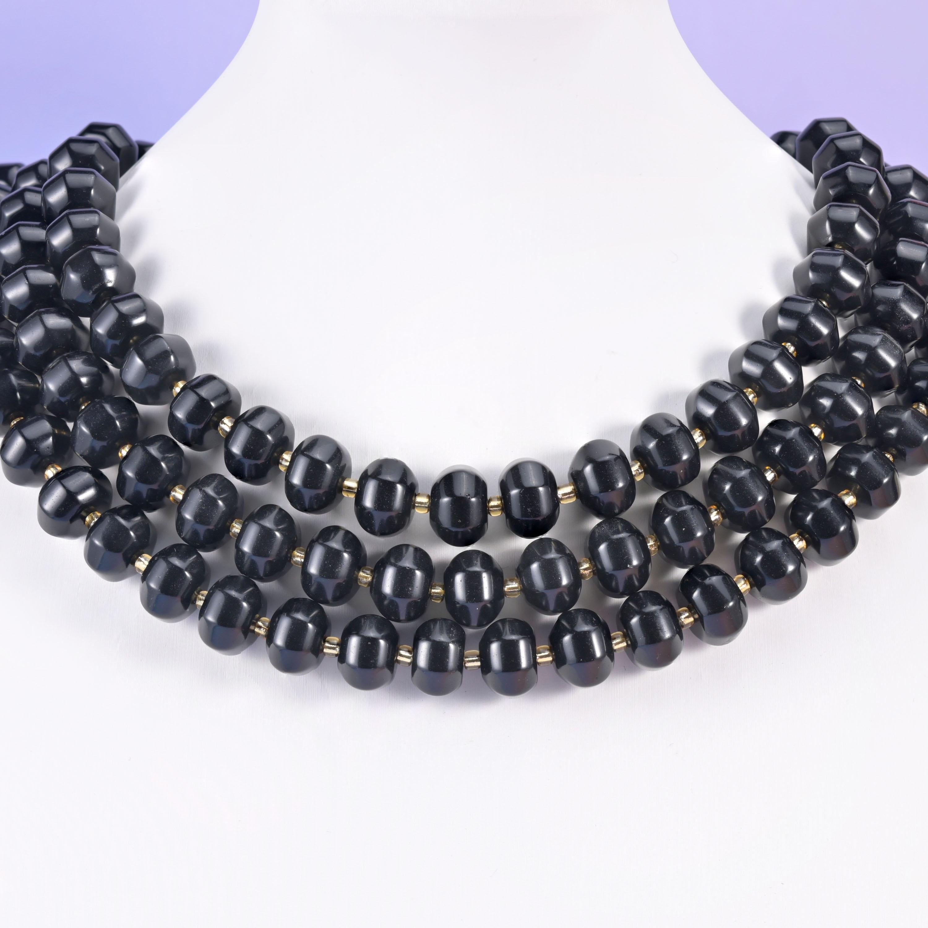 Multi-strand pumpkin rondelle necklace on a white display bust, deep black grooved beads at the collarbone