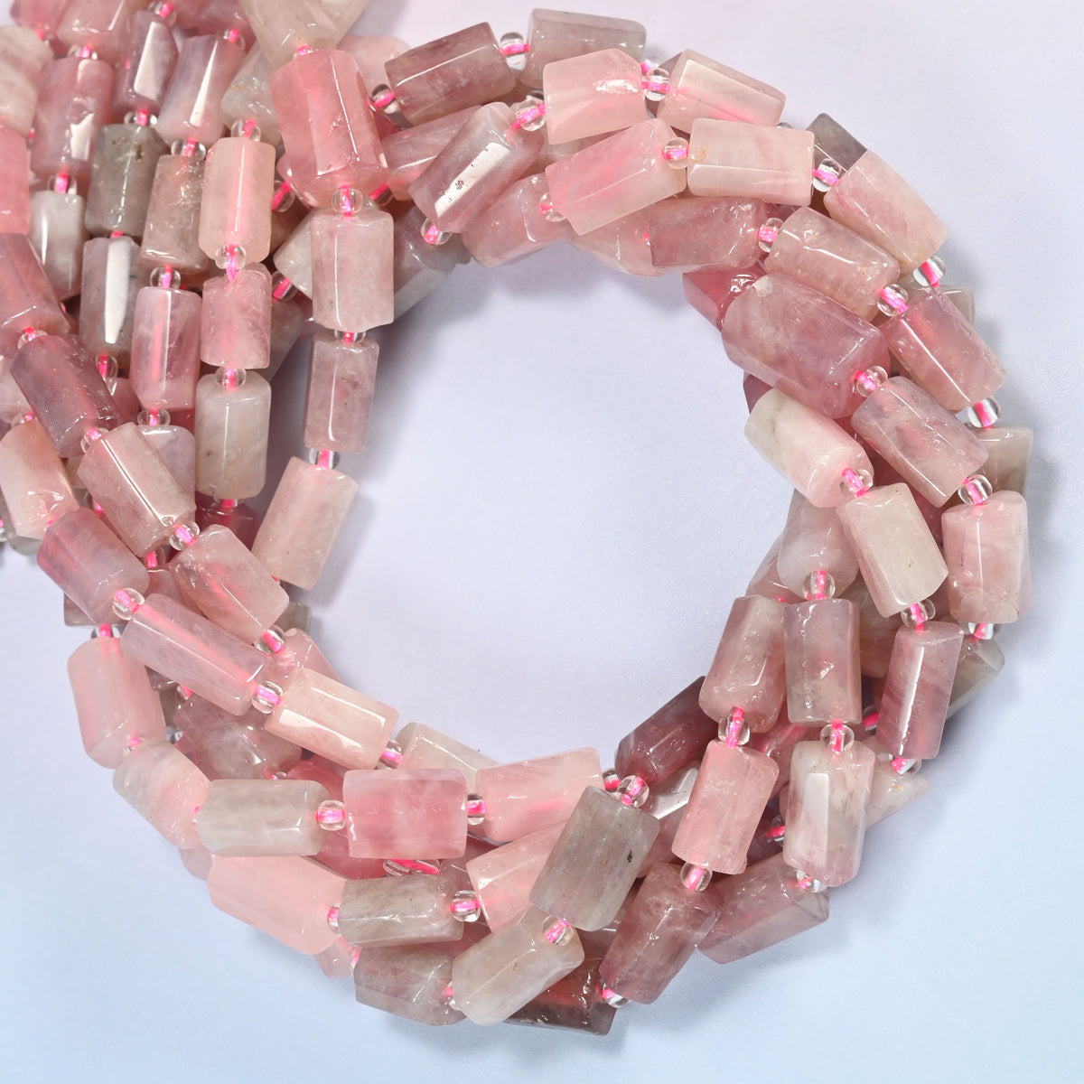 Madagascar multi color rose quartz faceted tube beads coiled in overlapping loops, milky pink and gray-mauve stone.