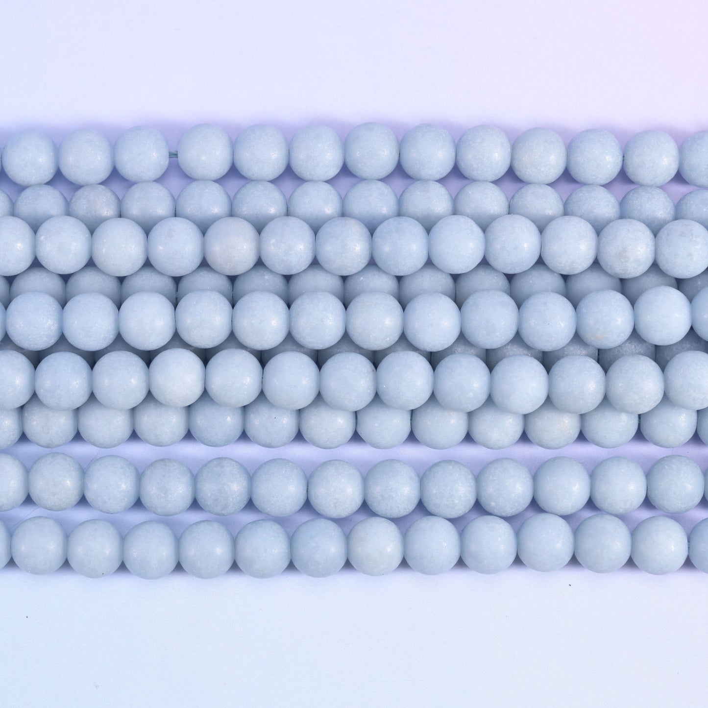 Pale powder blue rounds with a soft matte surface — no shine, no strong veining, just an even chalky sky blue running the length of the strand. One of the calmest, most consistent pastels in the shop.