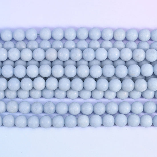 Pale powder blue rounds with a soft matte surface — no shine, no strong veining, just an even chalky sky blue running the length of the strand. One of the calmest, most consistent pastels in the shop.