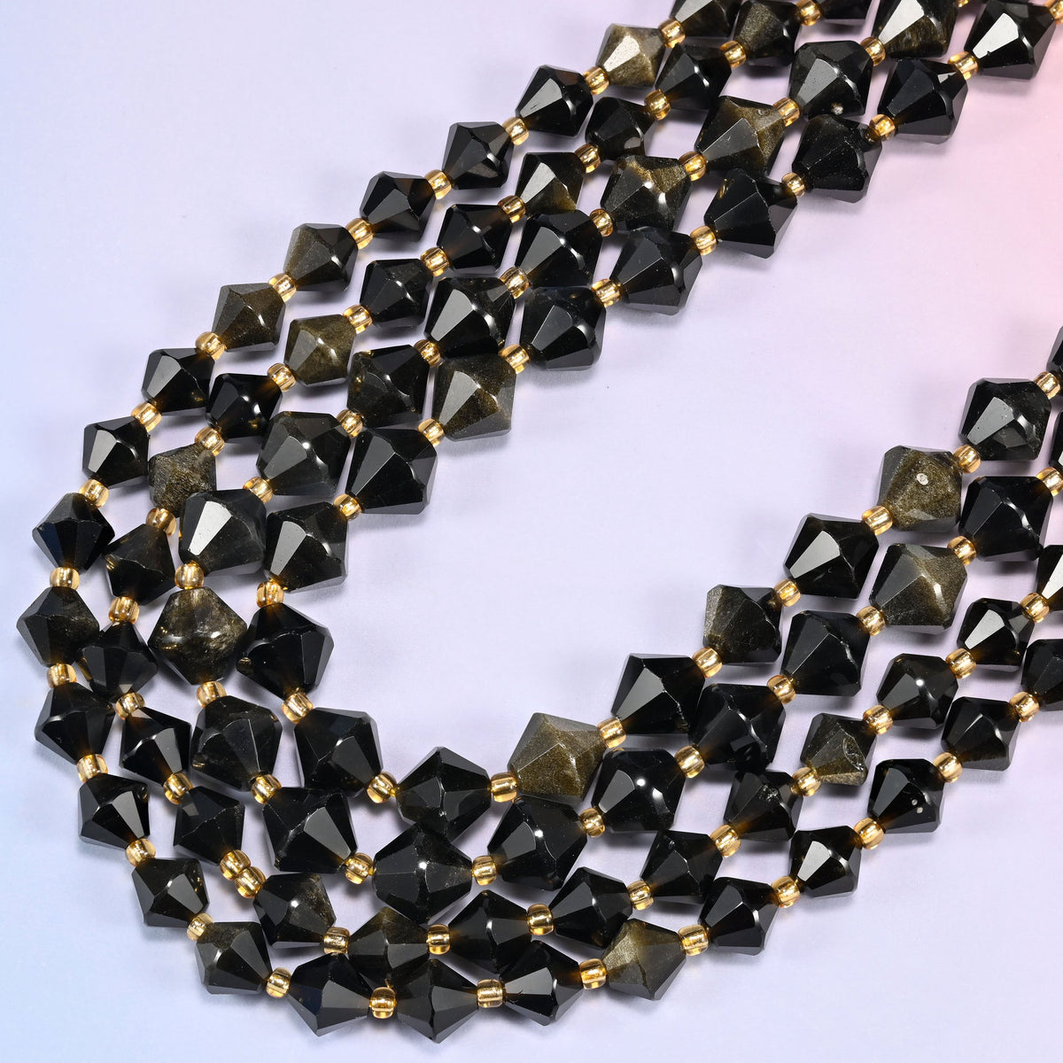 Gold obsidian bicone beads in a wide loop curving down and back, bronze and olive tones surfacing across the black body.