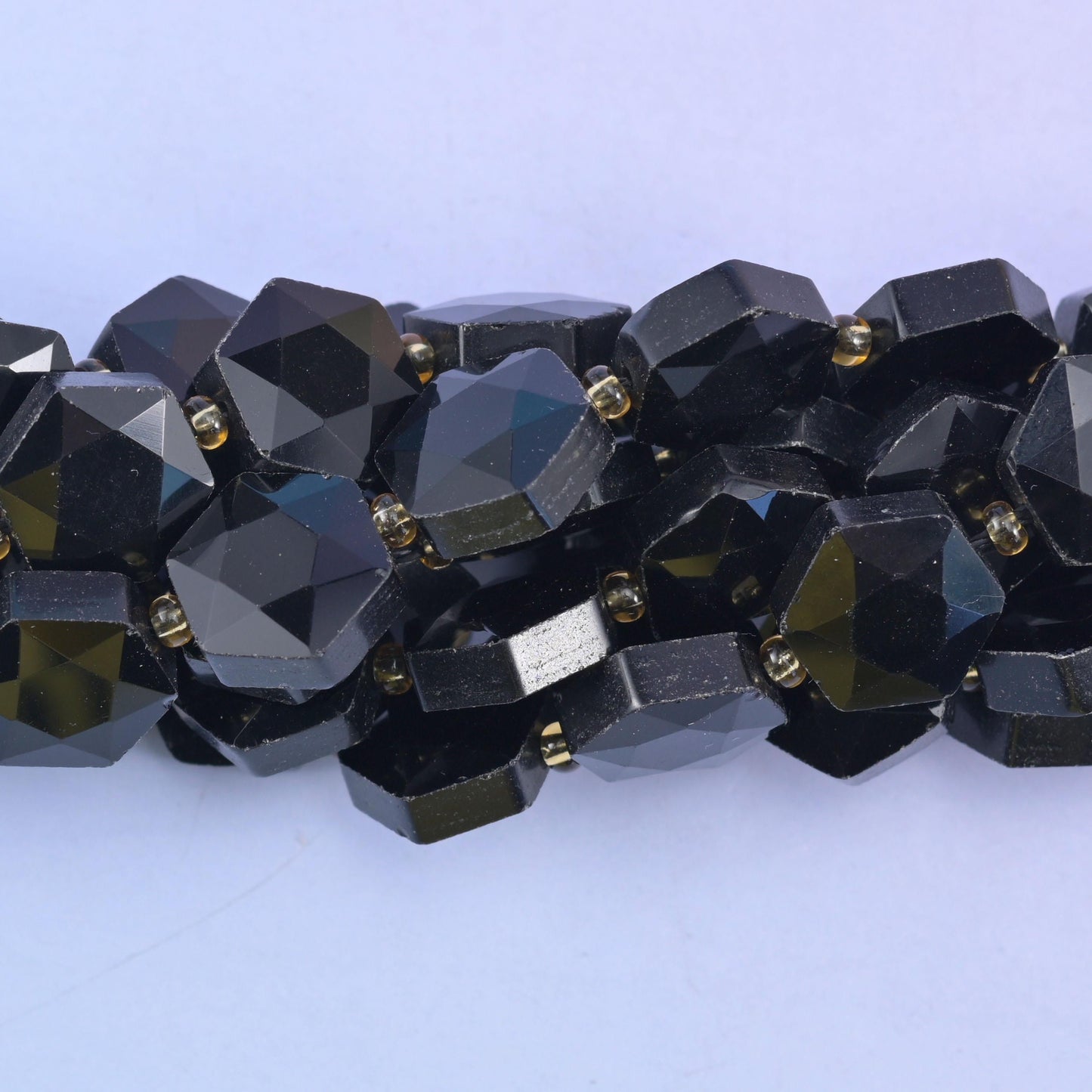 Macro of the faceted edges, glossy black obsidian picking up olive and silver glints
