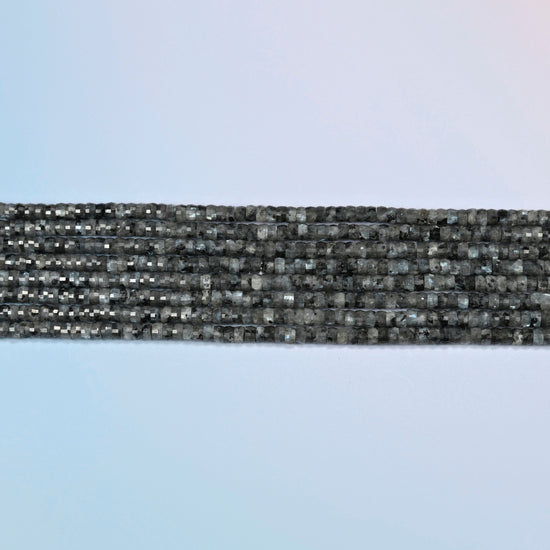 Several strands of black labradorite faceted heishi disc beads laid in straight rows