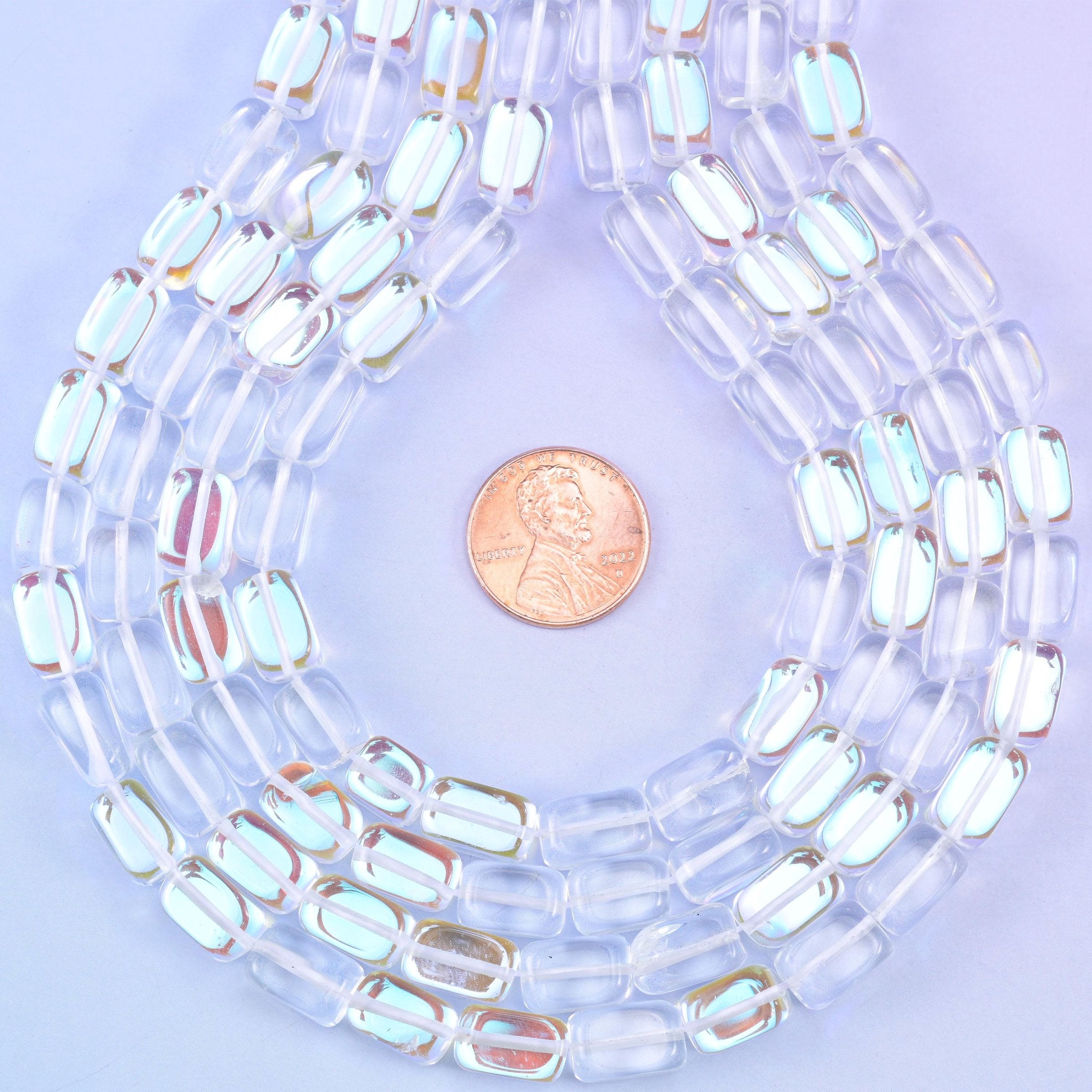 Crystal clear rectangle glass beads with a high gloss polish and a Mystic Aura coating that scatters pale rainbow light across each flat surface