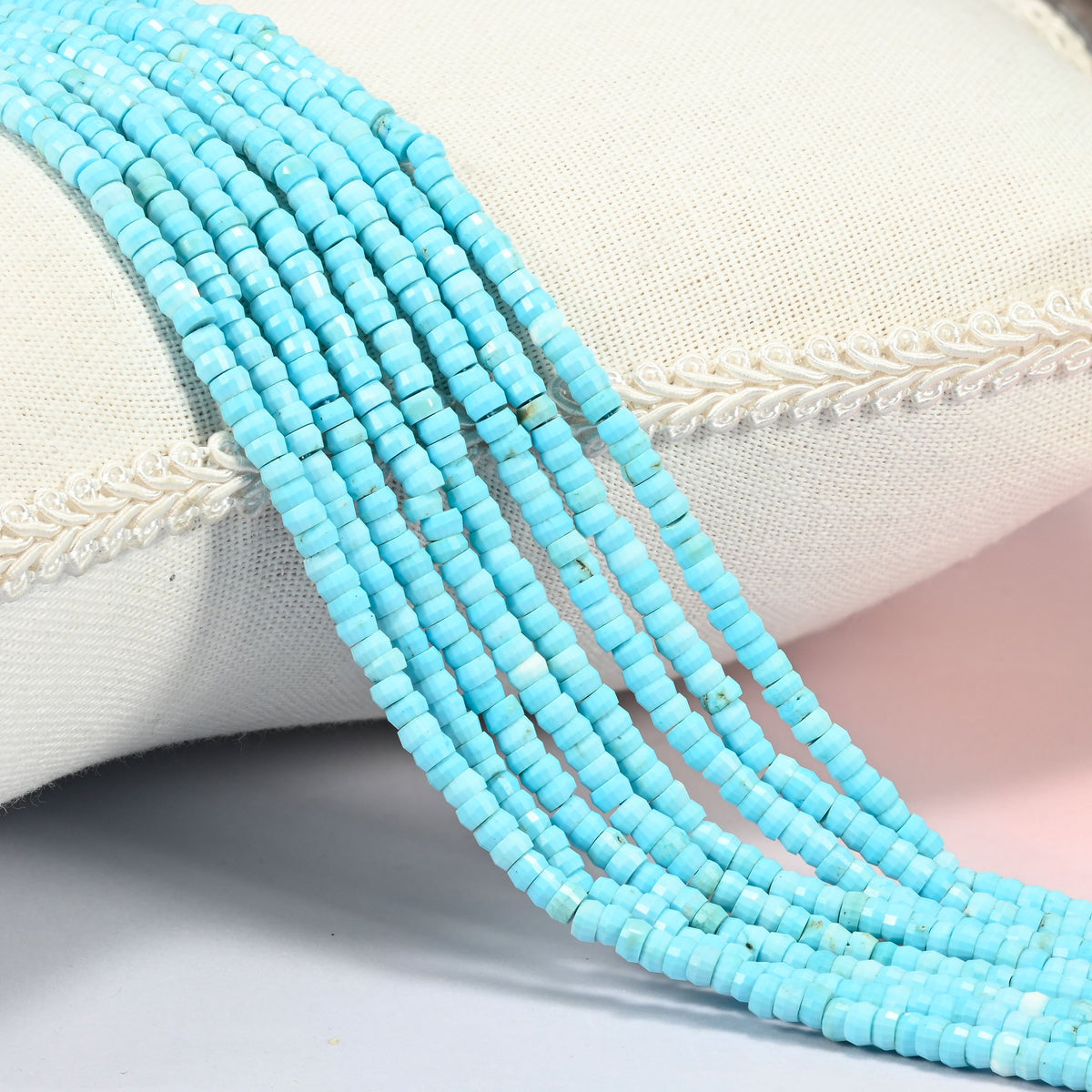 Dyed blue howlite faceted heishi disc beads 2x4mm, several strands draped over a white cushion