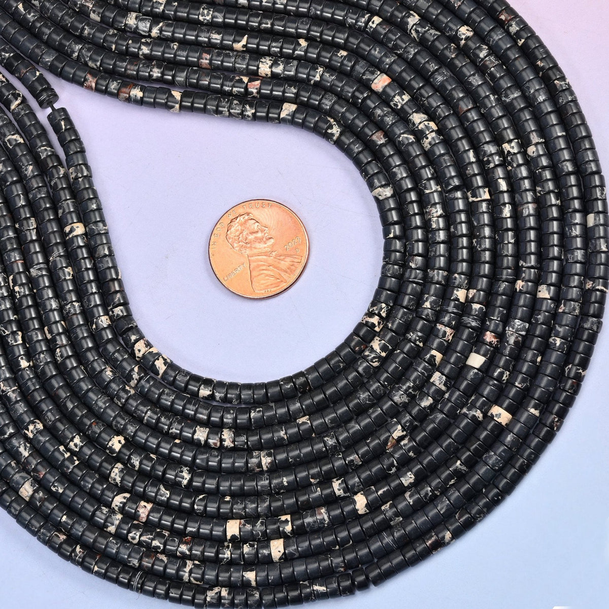 Deep black discs broken up by patches of cream and white marbling, polished flat and slim — a high-contrast neutral that reads graphic rather than plain.