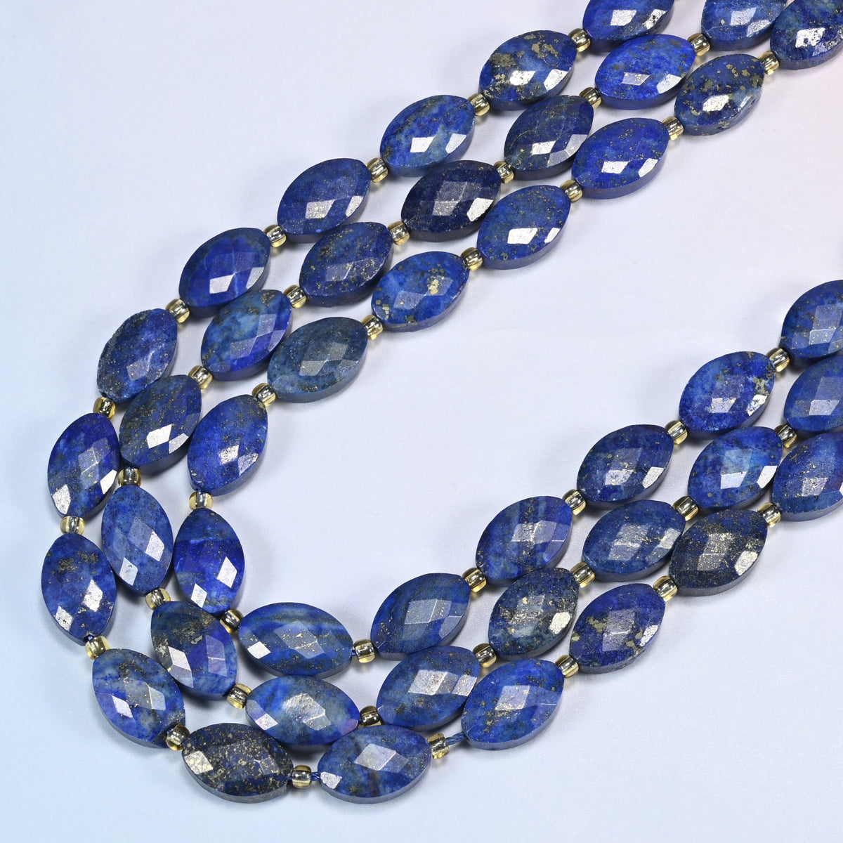 Lapis lazuli faceted flat oval beads in several strands curved into a wide U, deep royal blue stone with gold flecks