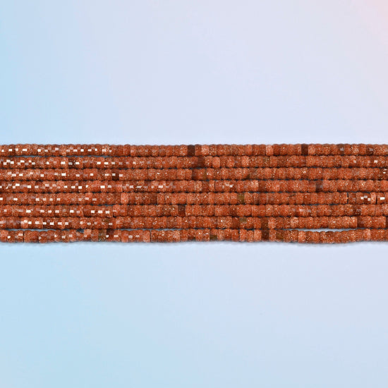 Several strands of gold sandstone faceted heishi disc beads laid in straight rows