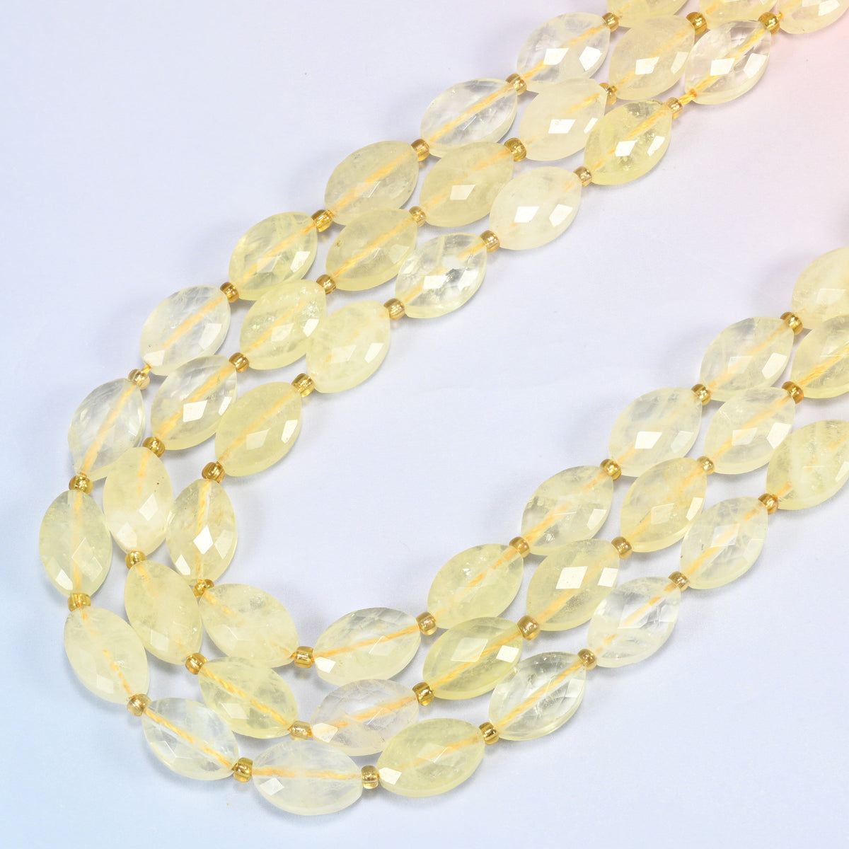 Citrine faceted flat oval beads in several strands curved into a wide U, light lemon yellow stone