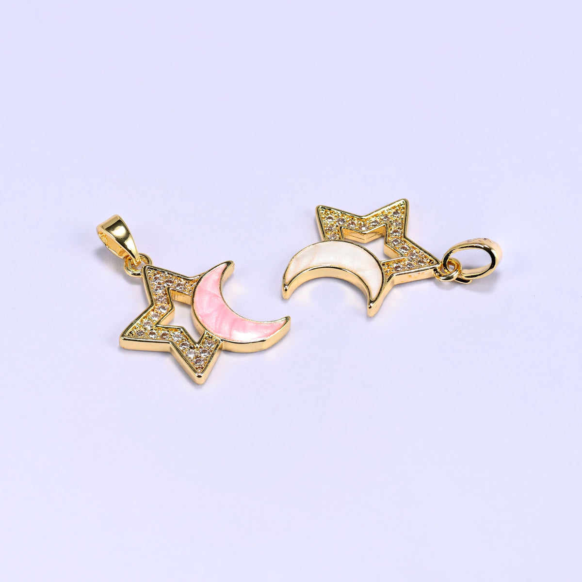 Two Star Shell Moon Zirconia Charms lying at an angle, one pink and one white, showing the crescent moon and openwork star from the side.