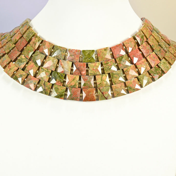 Natural unakite faceted flat square strands arranged as a layered collar on a white display bust, green and pink beads across the neck