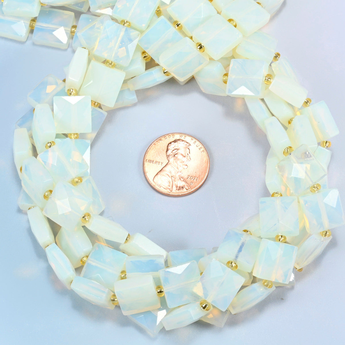 Opalite faceted flat square beads 10x10mm coiled in a loop around a US penny for scale, close-up of the faceted flat square shape