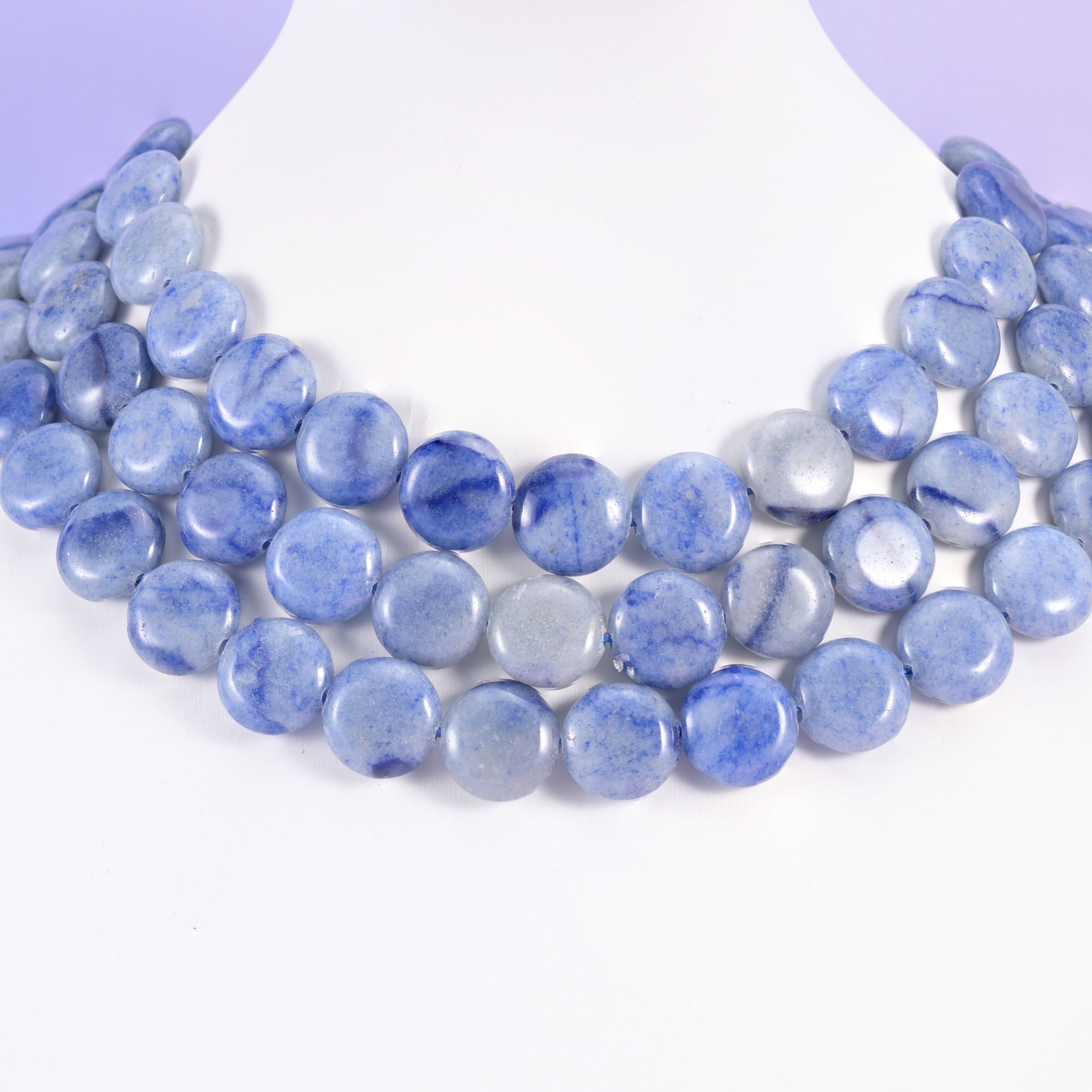 Layered blue aventurine coin necklace on a white bust form, three strands of soft denim-blue discs