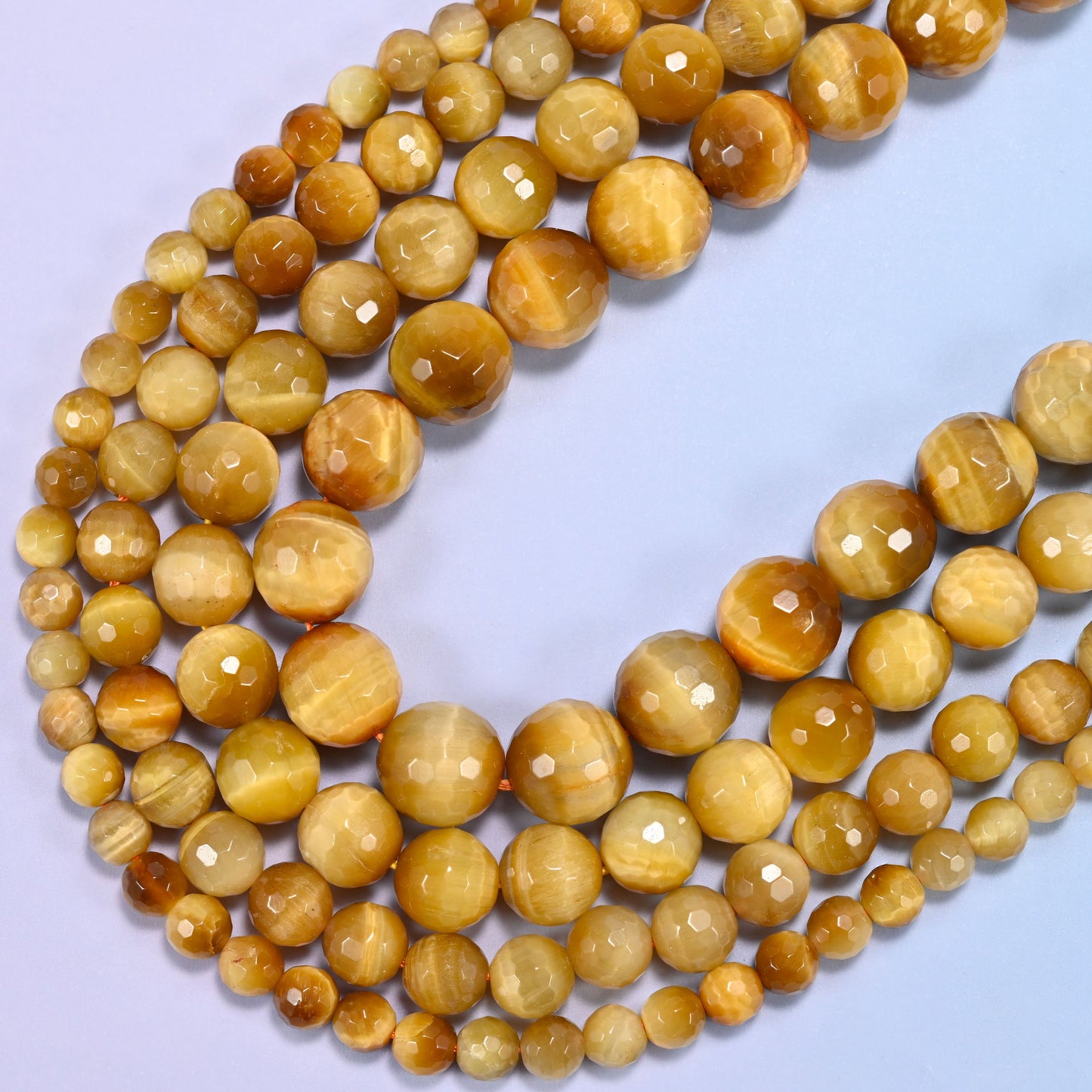 Macro detail of golden brown gold tiger eye bead surface, highlighting the faceted texture and shine.