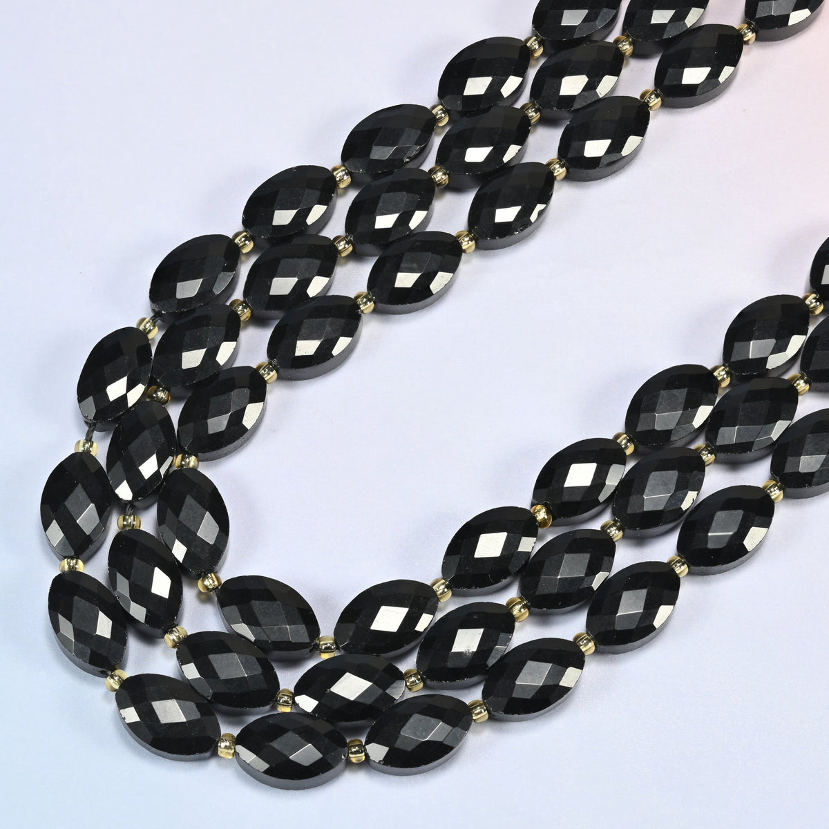 Black onyx faceted flat oval beads in several strands curved into a wide U, solid glossy black stone