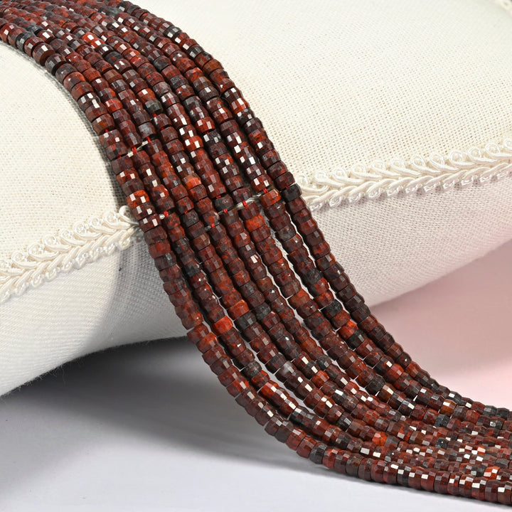 Zhanguo red agate faceted heishi disc beads 2x4mm, several strands draped over a white cushion