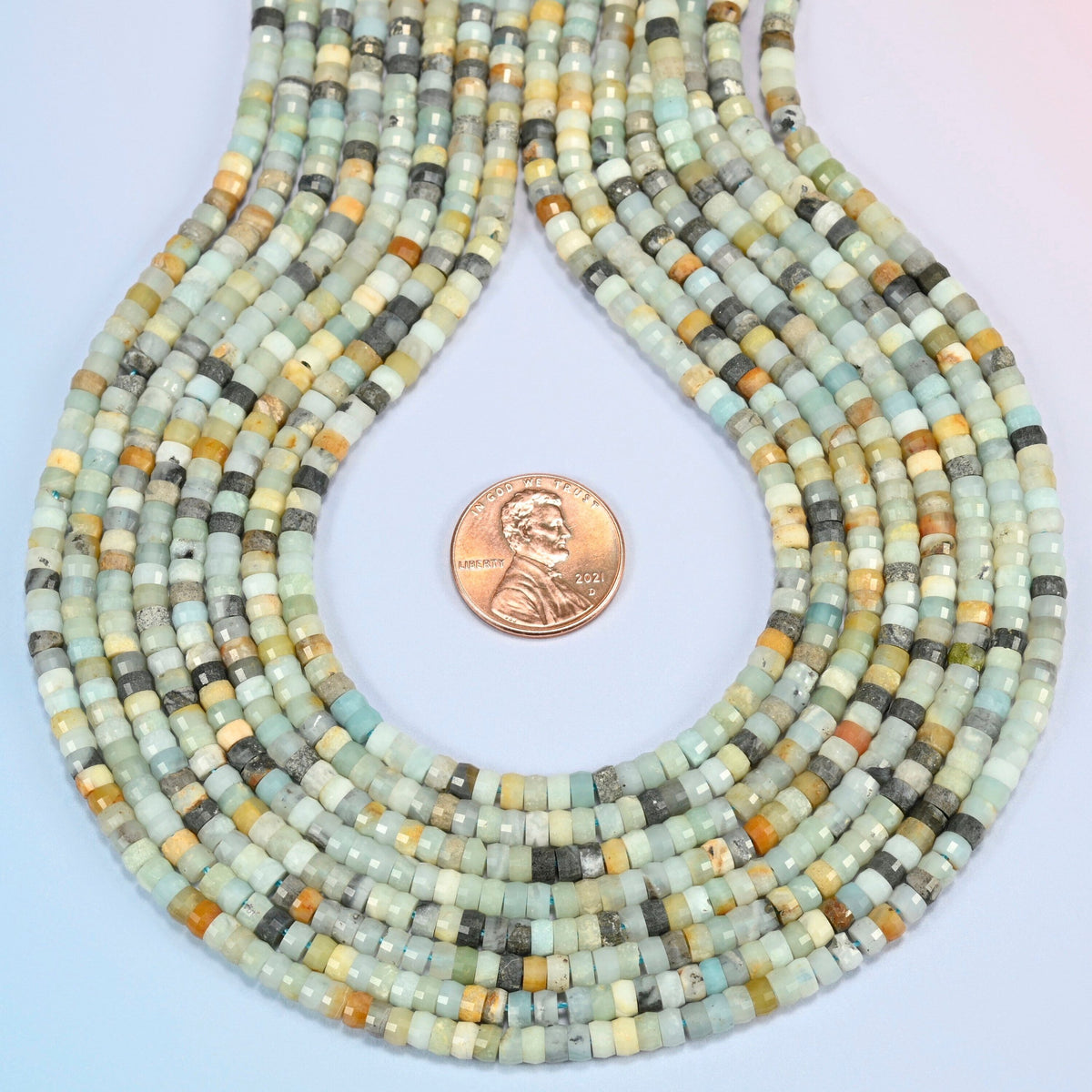 Multi-color amazonite faceted heishi disc strands formed into a teardrop loop around a US penny for scale