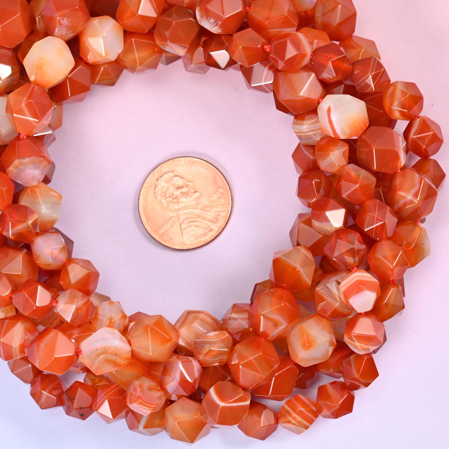 Dyed Red Stripe Agate beads coiled around a US penny, drill hole approximately 1.0mm, warm orange and cream banding