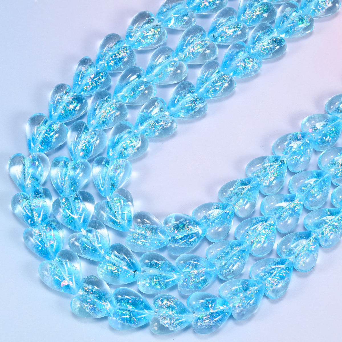 Iridescent light blue heart glass beads in looped strands, clear edges with shimmering blue centres