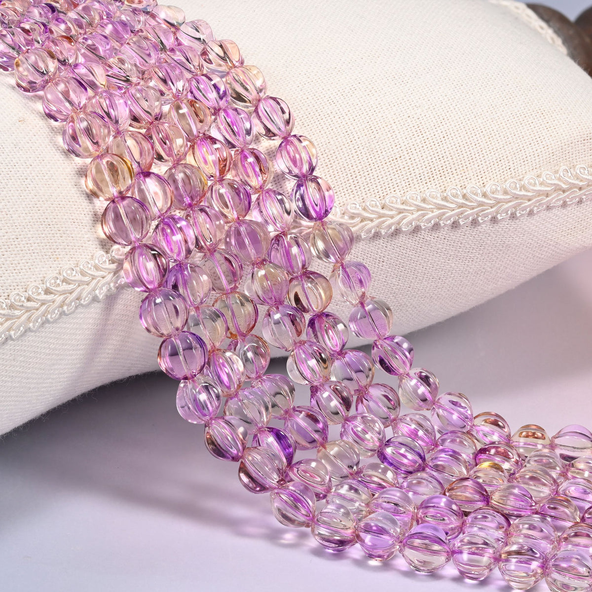 Clear purple gold pumpkin glass beads, 8mm fluted melon rounds, several strands draped forward in rows.