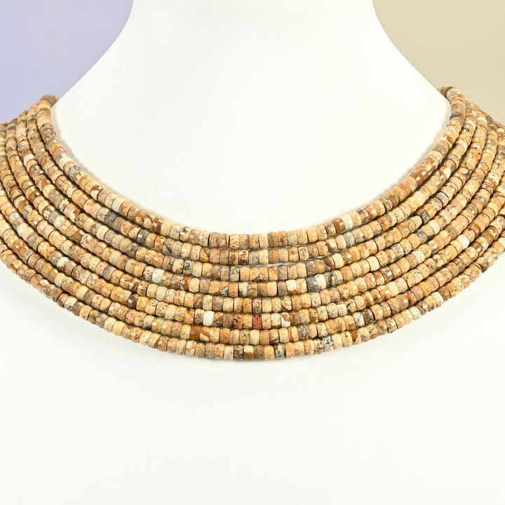 Picture jasper faceted heishi disc strands arranged as a layered collar on a white display bust, tan beads across the neck