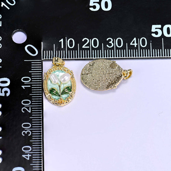 Enamel Oval Tulip Flower Pendants measured on a black millimetre ruler, the mint pendant beside its gold back, both close to 20x13.5mm.