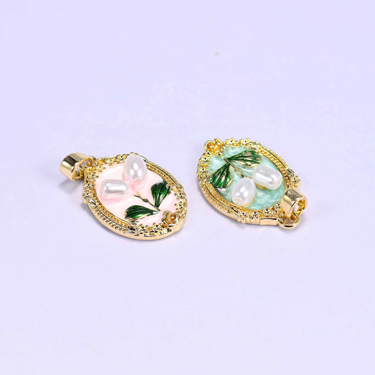 Enamel Oval Tulip Flower Pendants tilted at an angle, peach and mint side by side so the raised pearl blooms and the bail are visible.