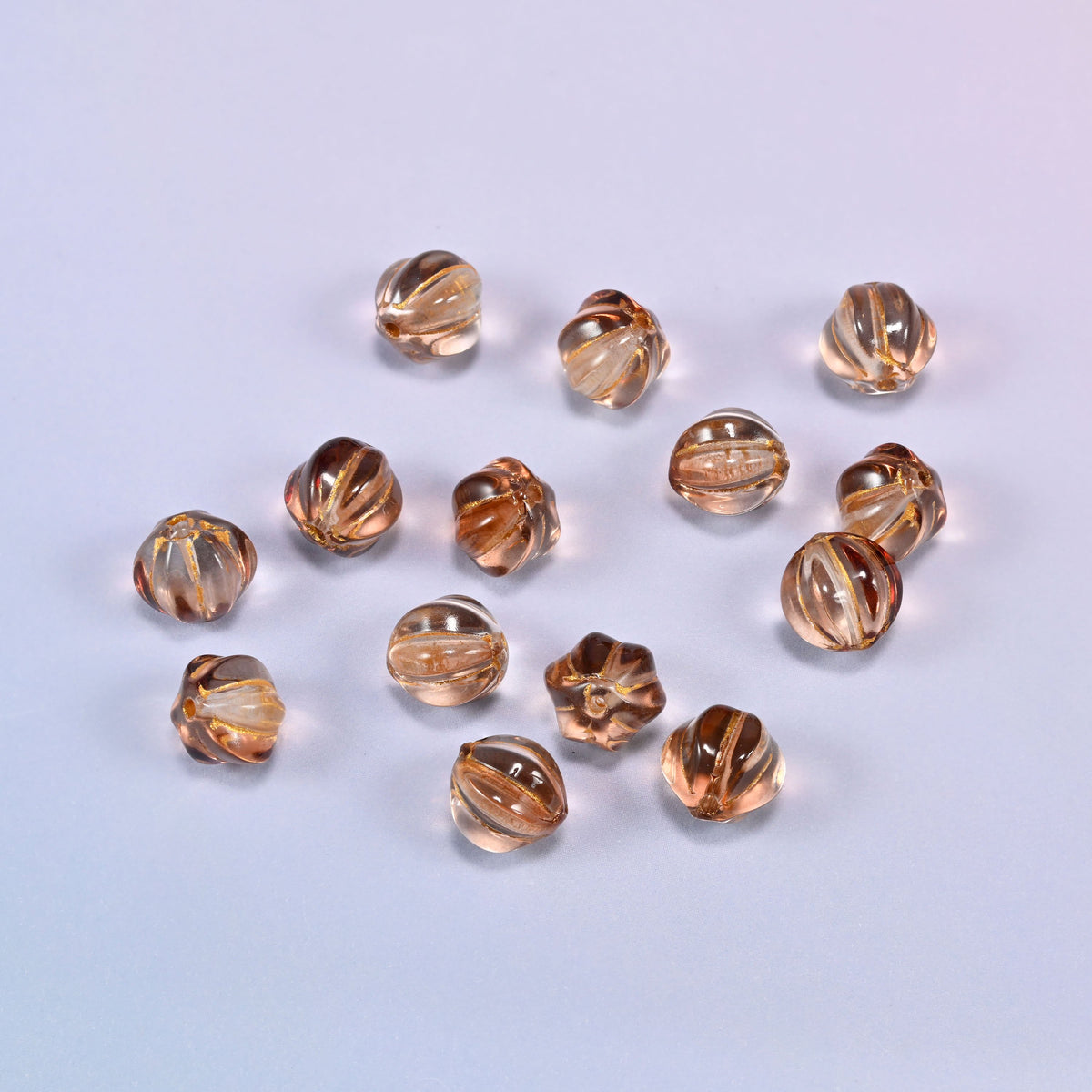 A scattered group of loose 8mm brown pumpkin glass beads, showing the melon ribs and the drill holes.