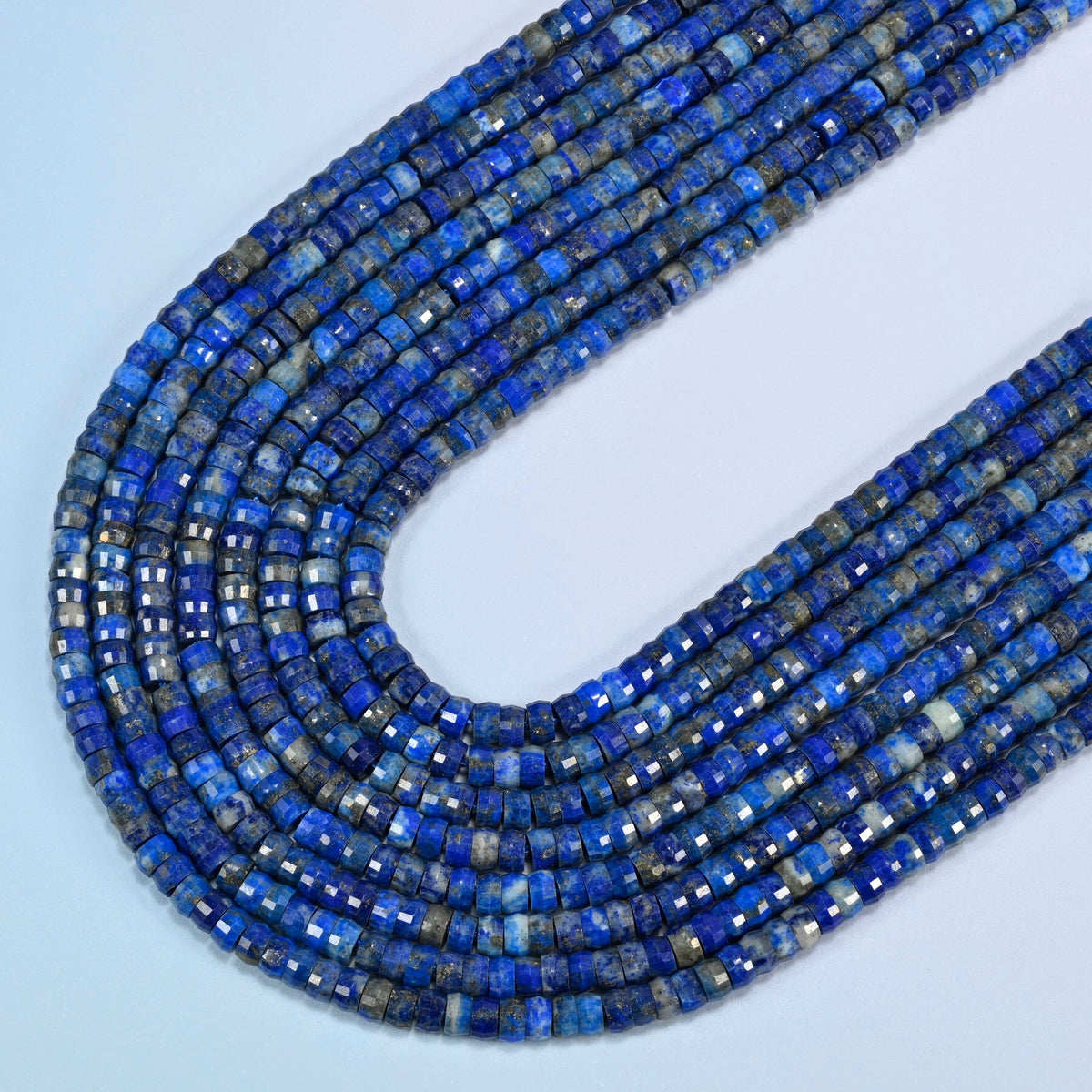 Lapis faceted heishi disc beads in several strands curved into a wide U, royal blue stone with white and gold flecks