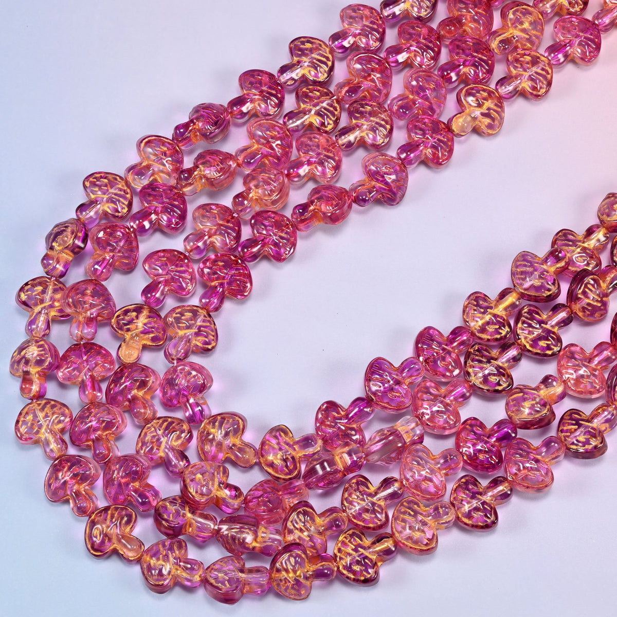 Pink gold flat mushroom glass beads laid in a narrow chevron, the two limbs running close together down to a point.