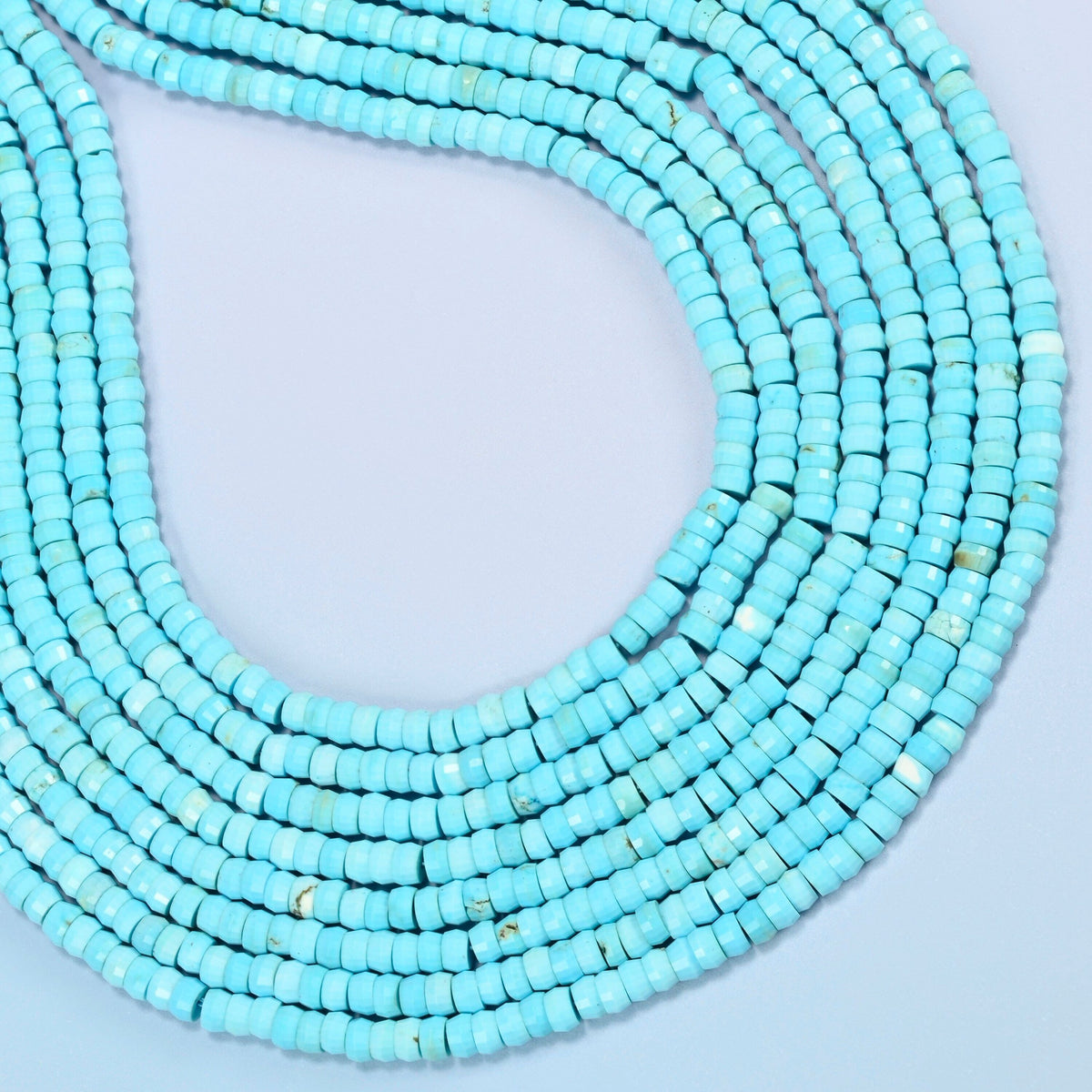Dyed blue howlite faceted heishi disc beads curved into an open loop, turquoise blue beads with fine light veining
