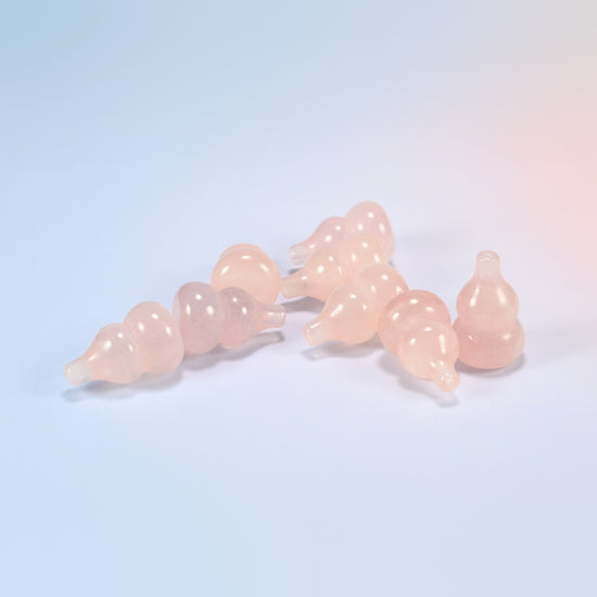 A pile of small natural rose quartz gourd carvings, light pink