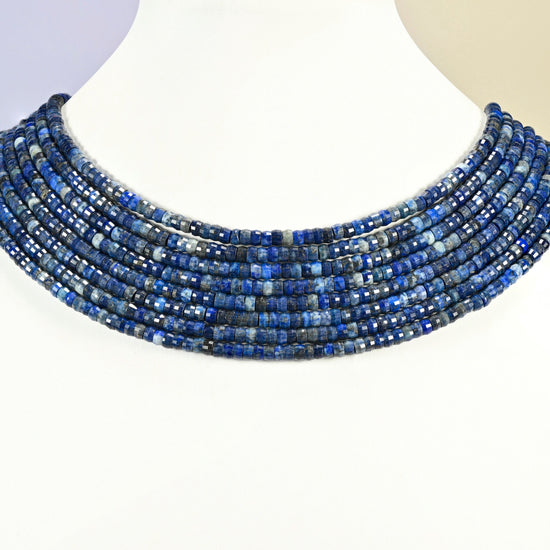Dark blue lapis faceted heishi disc strands arranged as a layered collar on a white display bust, dark blue beads across the neck